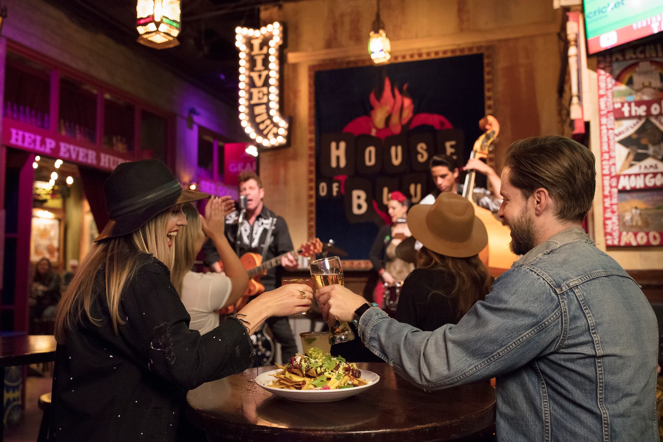 Two people cheers while sitting at a table facing a House of Blues stage