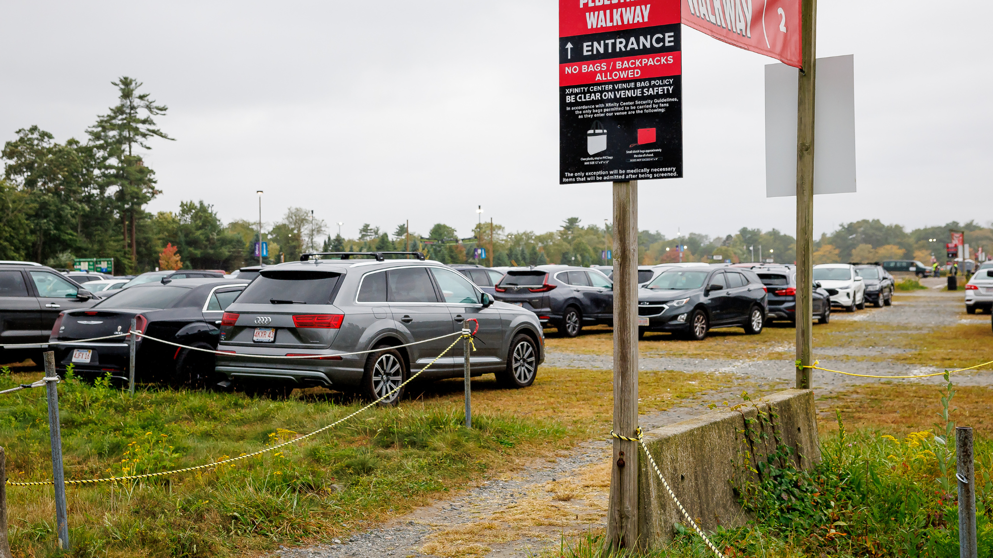 A grassy and gravel parking lot filled with cars.