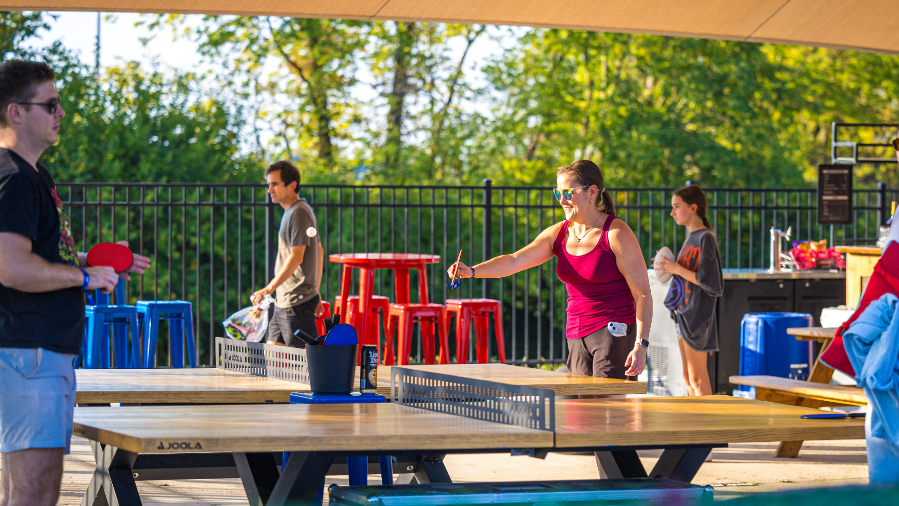 Fans inside the Tailgate Lounge playing table tennis, with high top chairs and tables in the background. 