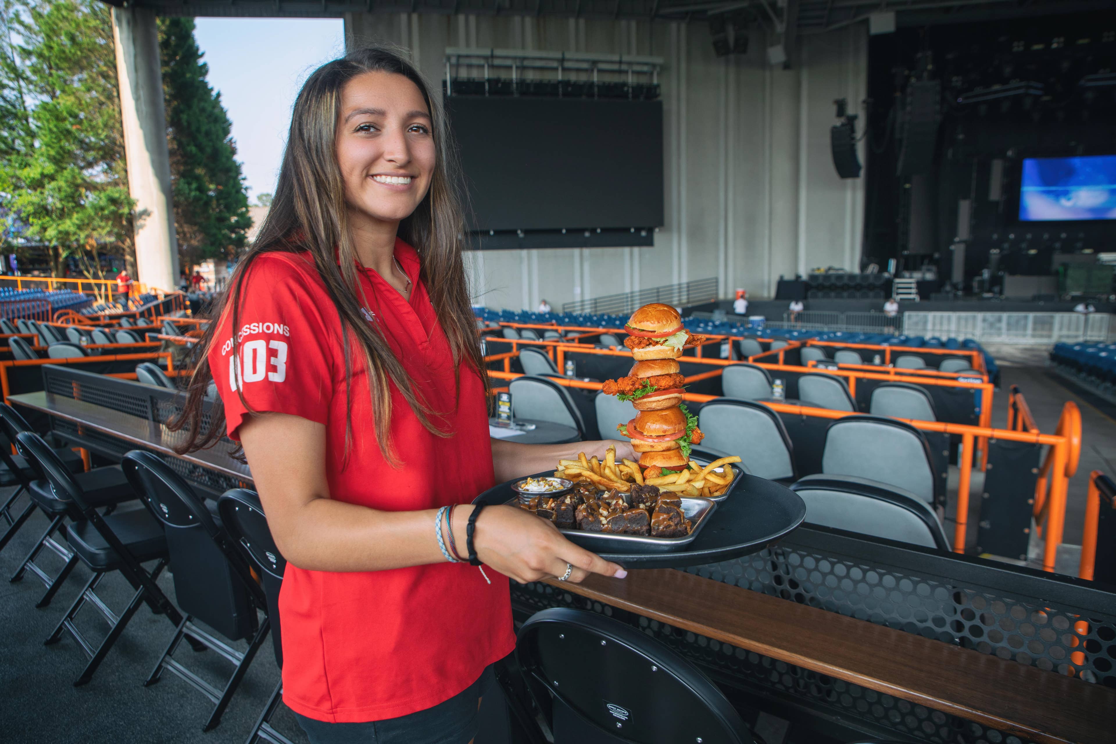 A young lady holding a tray with sandwiches on it