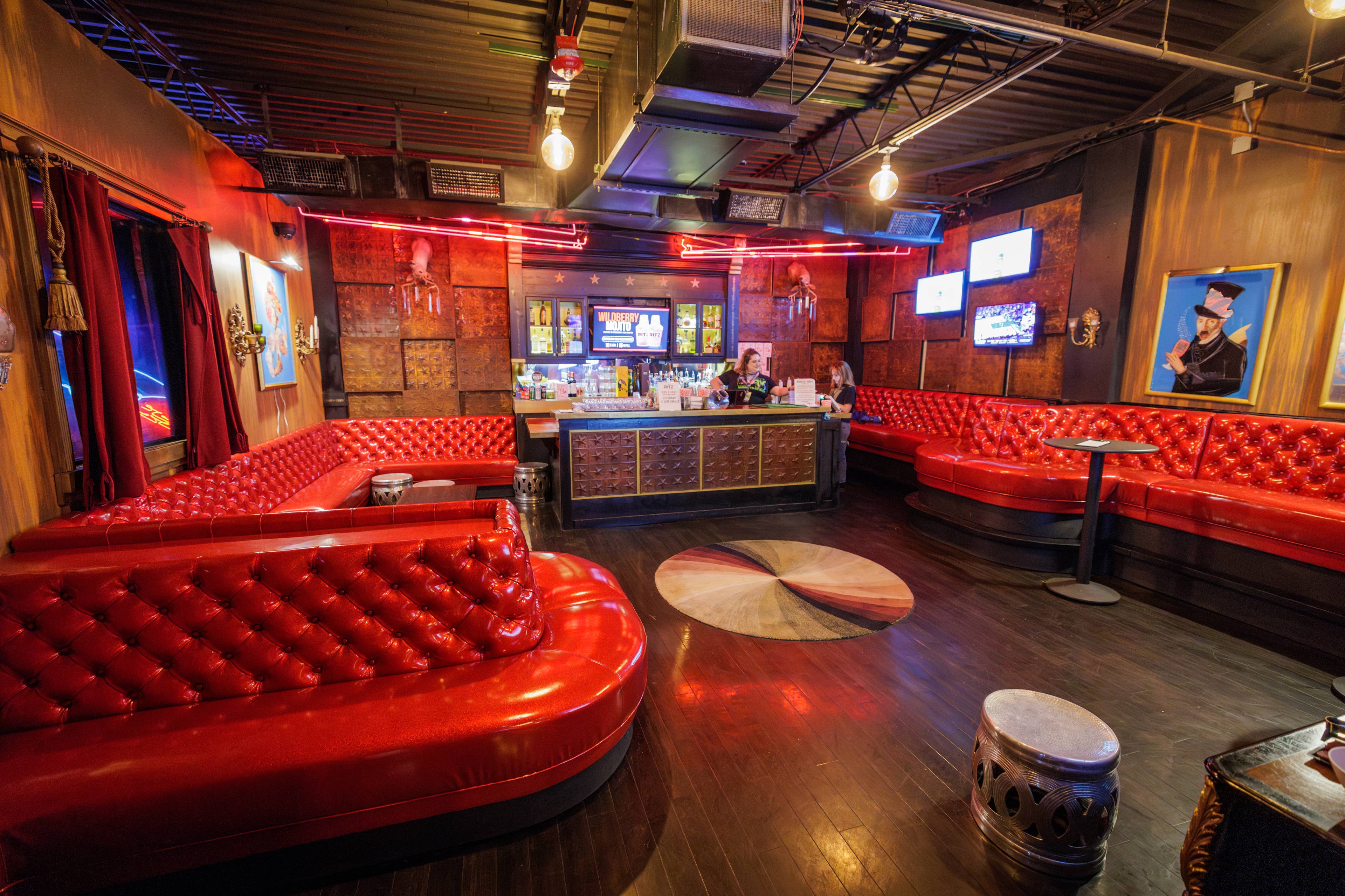 A small room with bar and alcohol bottles and red shiny couches