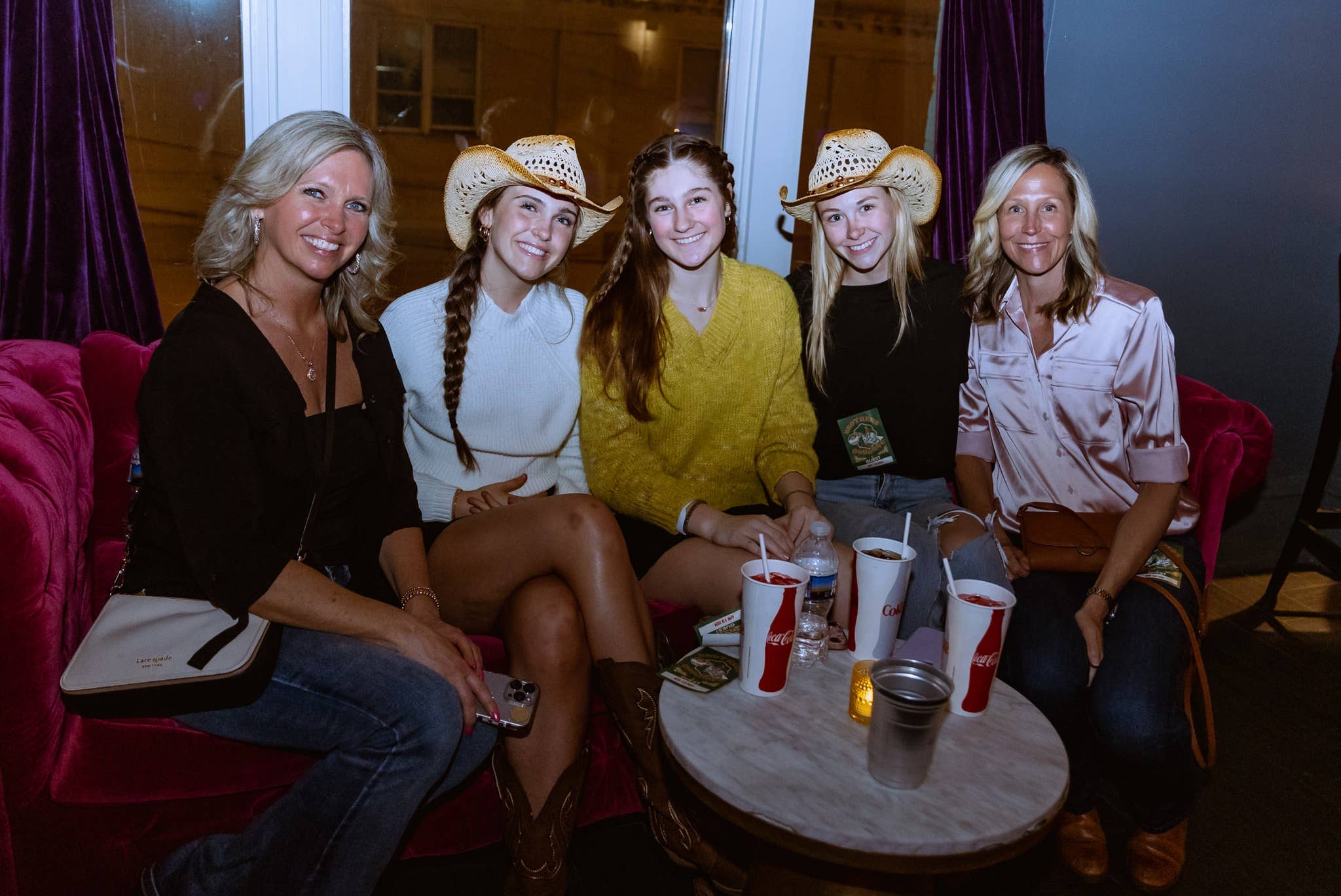 Five people sitting on a couch and smiling at the camera