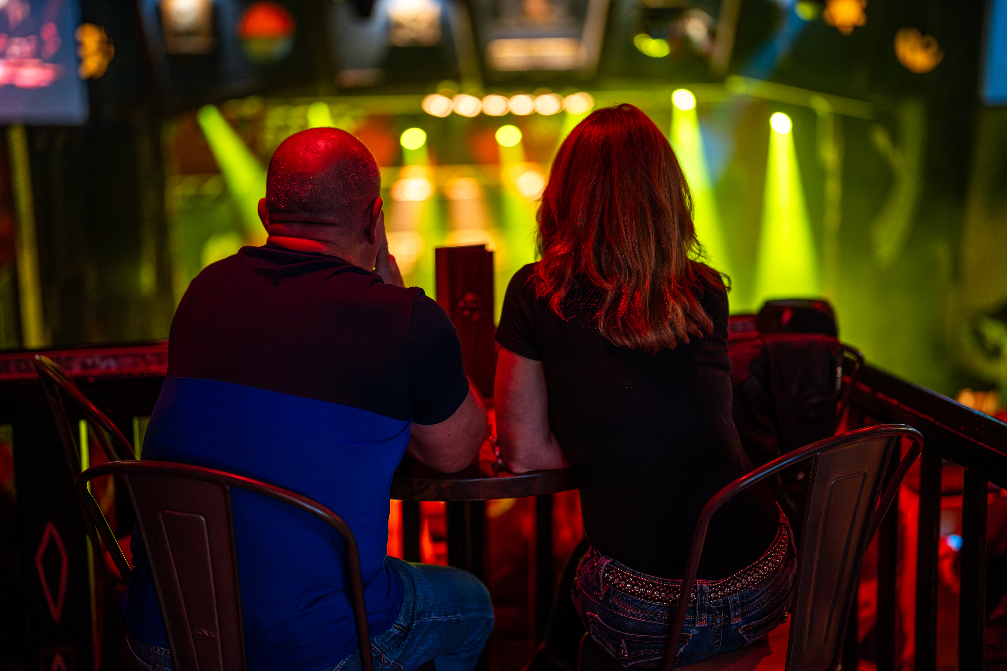 Two people sitting at a table overlooking a stage during a concert.