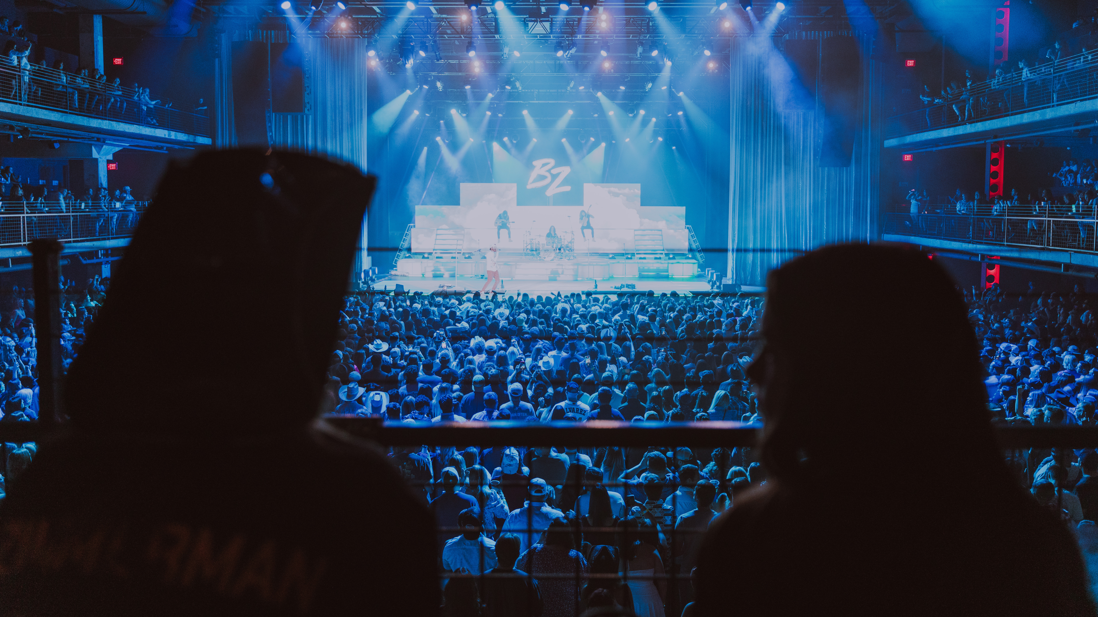 Two people overlooking a crowd of people at a concert venue. 