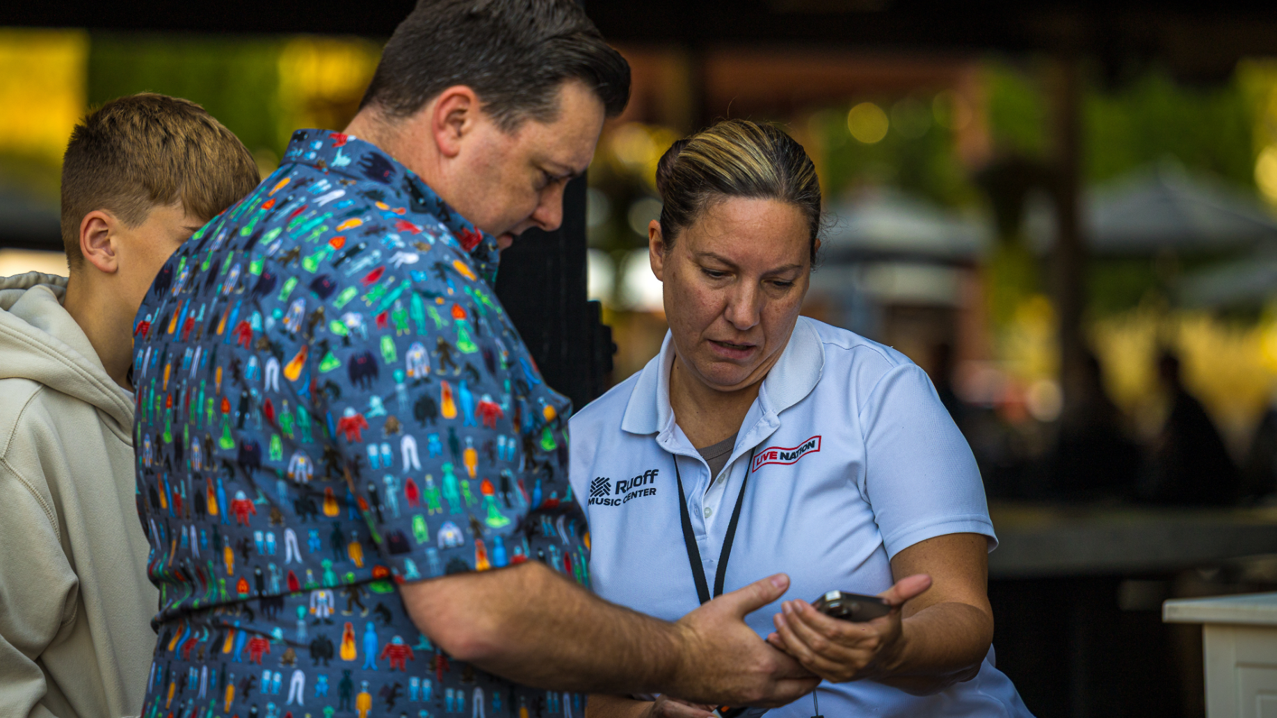 An employee helping a fan with their mobile ticket to get into the venue.