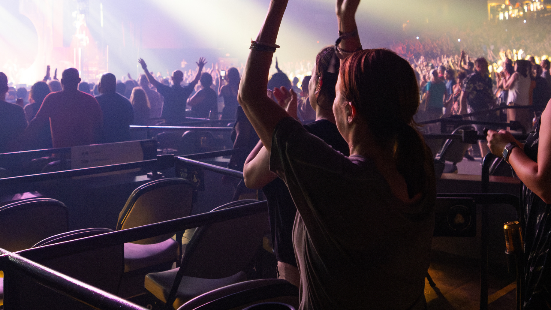 A fan in a box seat cheers on a show.