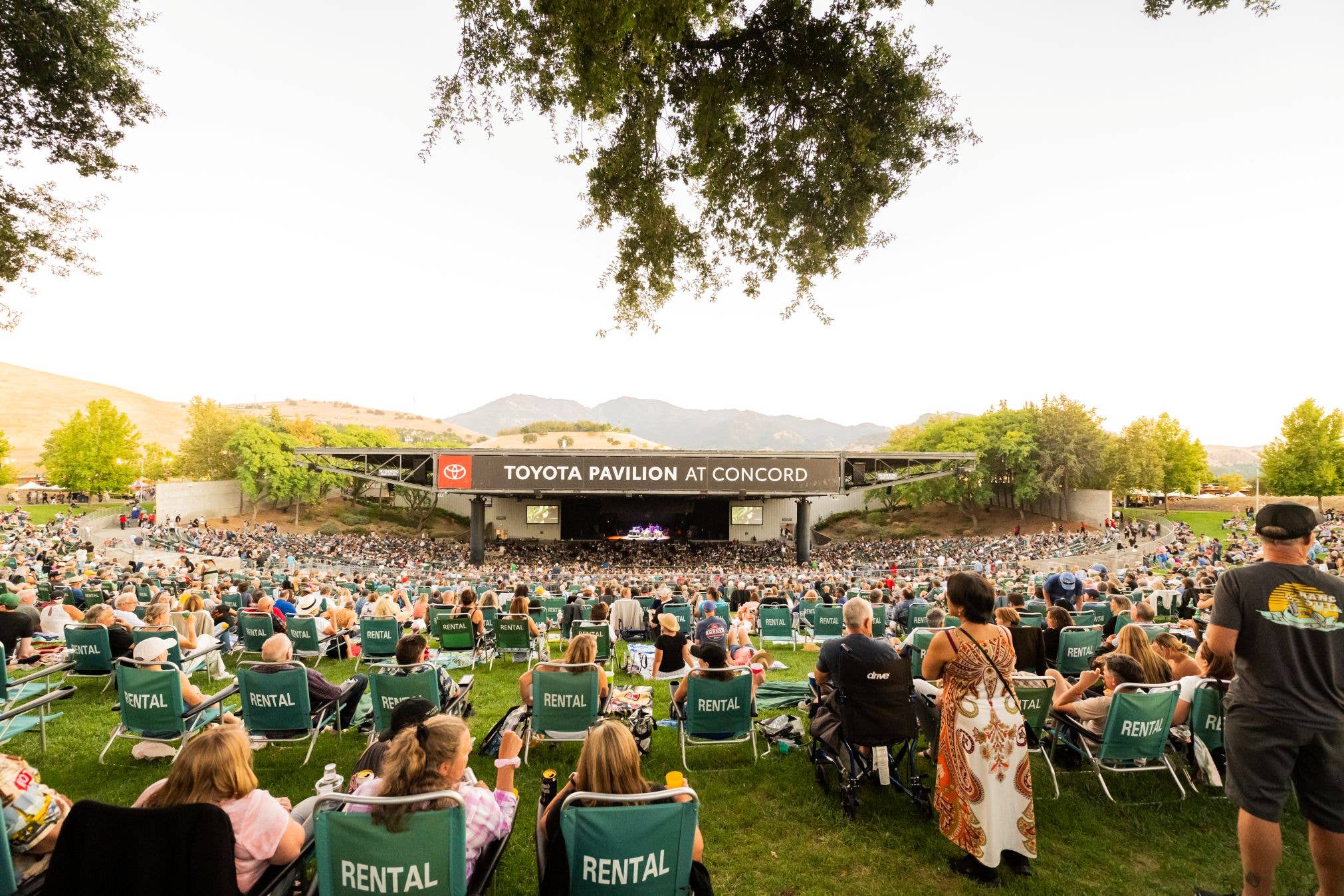 The lawn at Toyota Pavilion at Concord is shown with people sitting in lawn chairs facing the stage