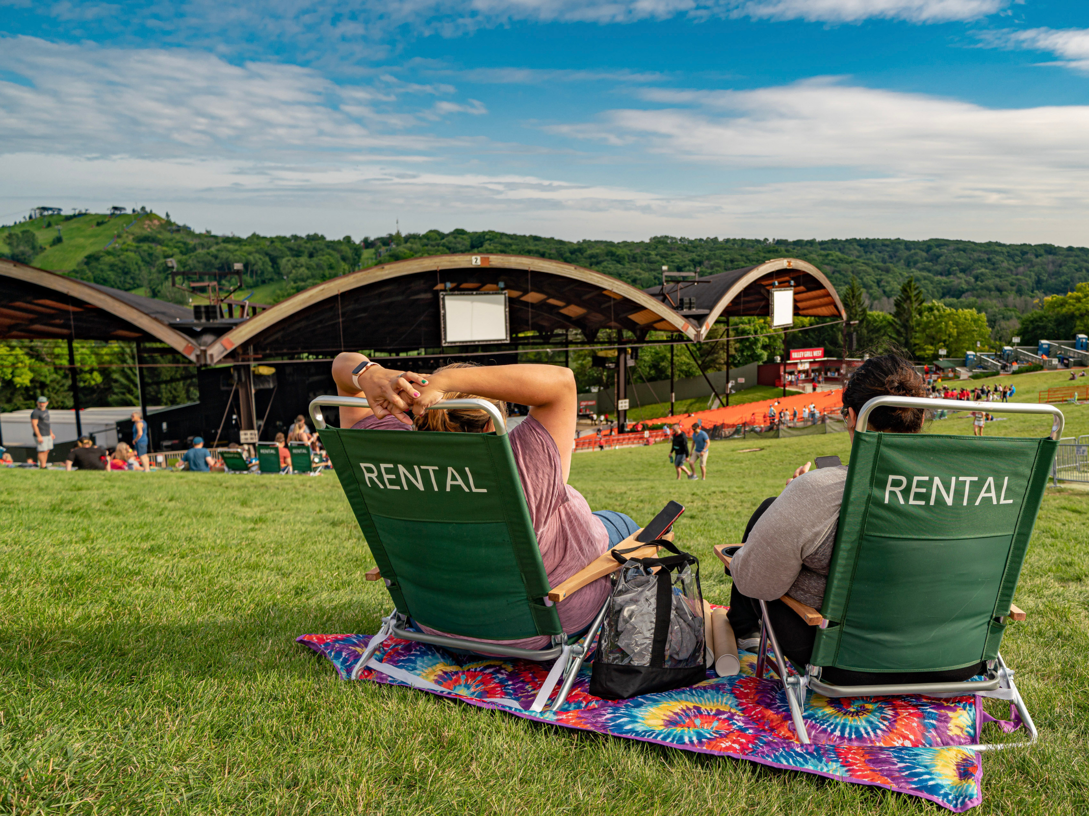 Two people sitting on rental chairs on the lawn at Alpine Valley Music Theatre.