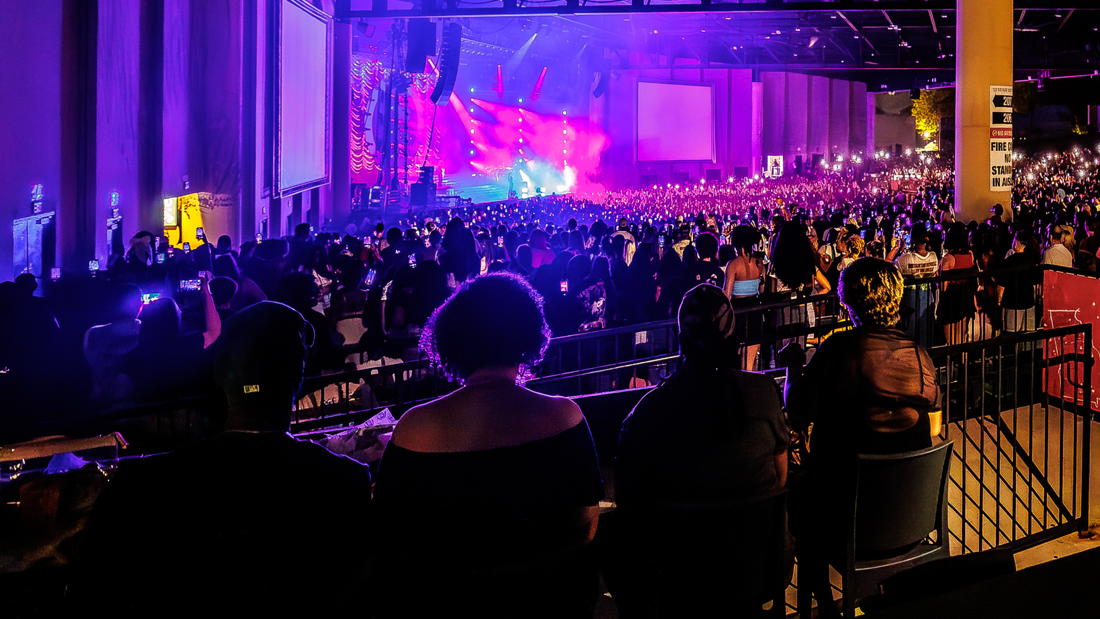 View of a live concert from a premium seating area with guests watching the illuminated stage