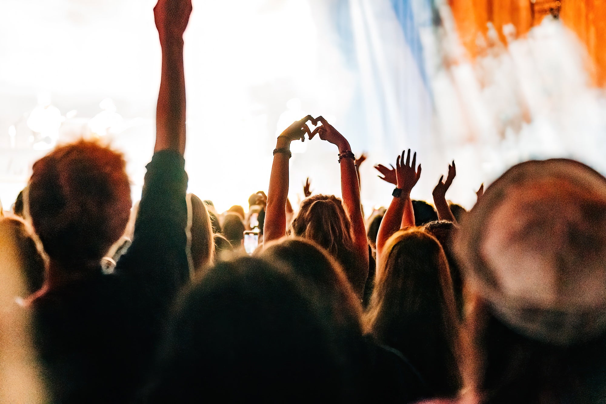 Fans in a crowd with someone making the heart sign with their hands