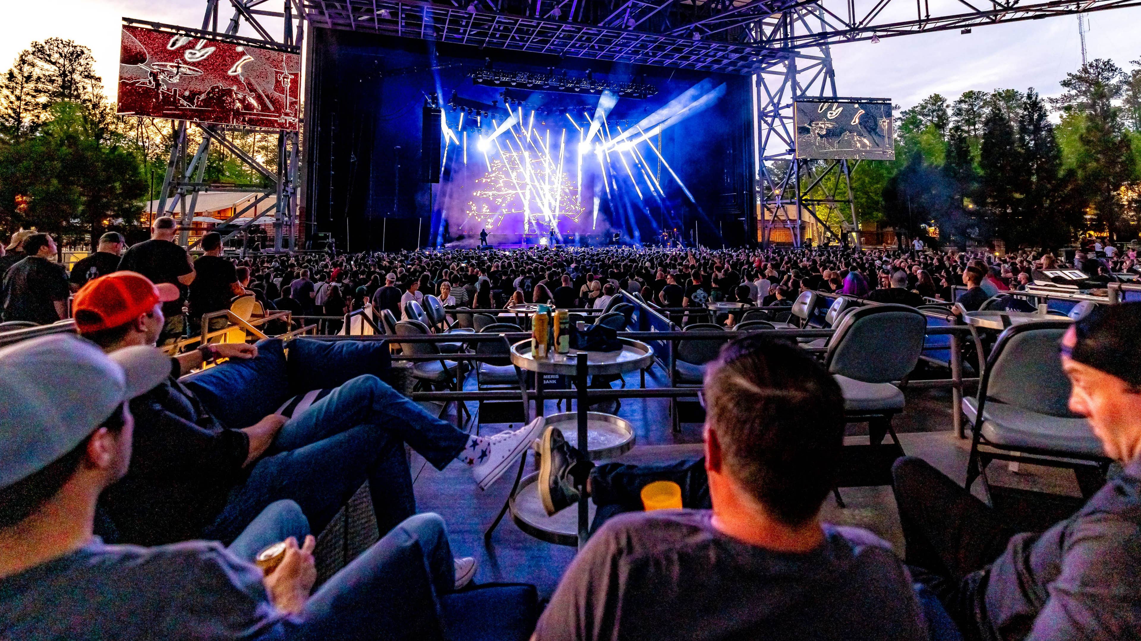 A group of fans sitting at a table in a VIP Box seat watching a concert
