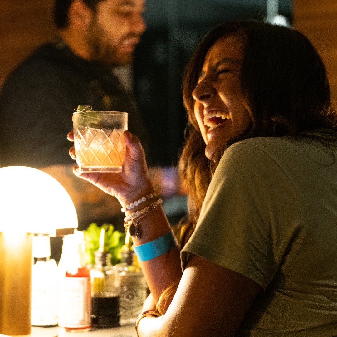 A woman is enjoying a drink and smiling at Good Luck Lounge