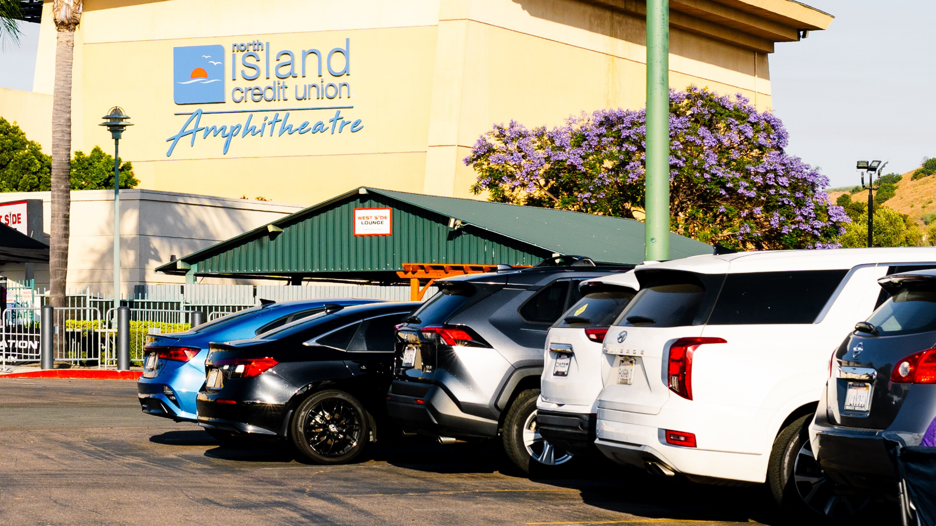 Cars parked in a paved parking lot right in front of North Island Credit Union Amphitheatre.