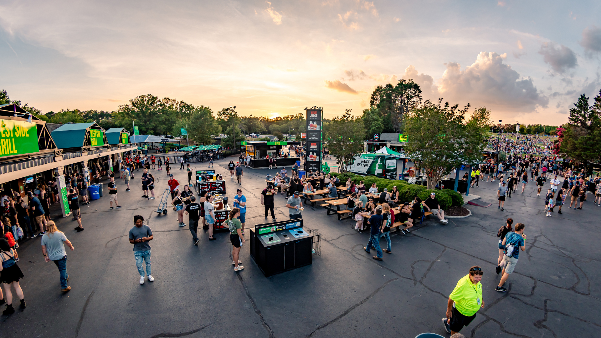 People walking around the concessions area of a concert venue and people sitting while eating and drinking