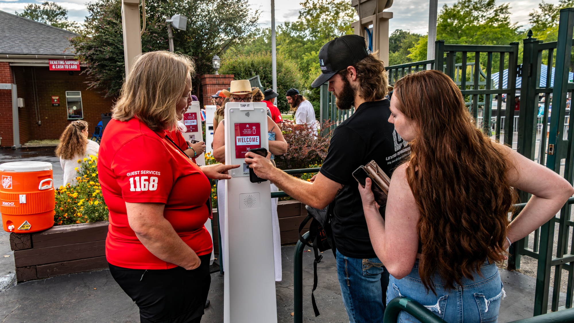 An employee helps two fans scan their ticket to get into the venue.