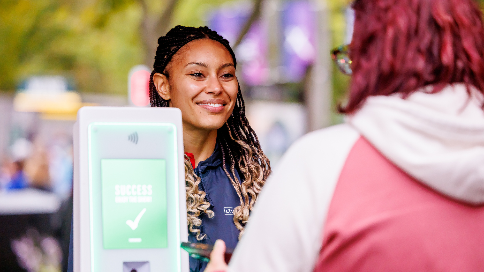 An employee smiling and a fan scanning her ticket to get into the venue.