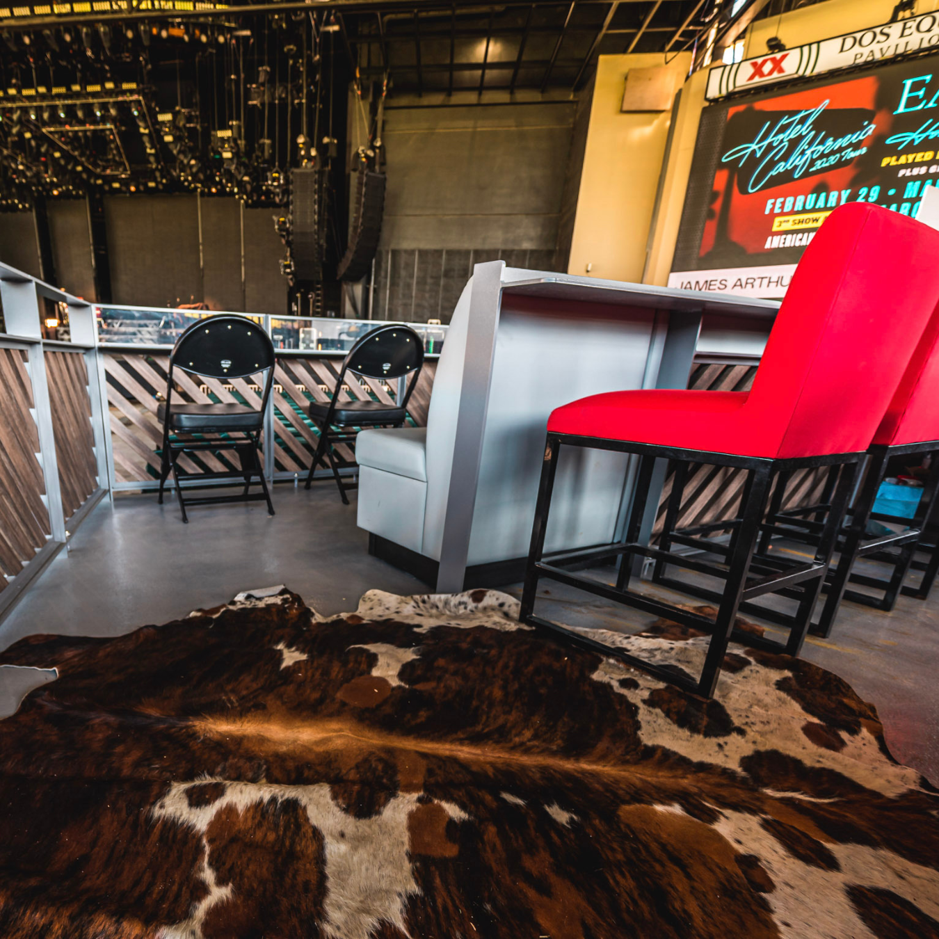 A view of the box seats, an entire cut-out area with a gray bar and tall, red chairs, level with the stage.