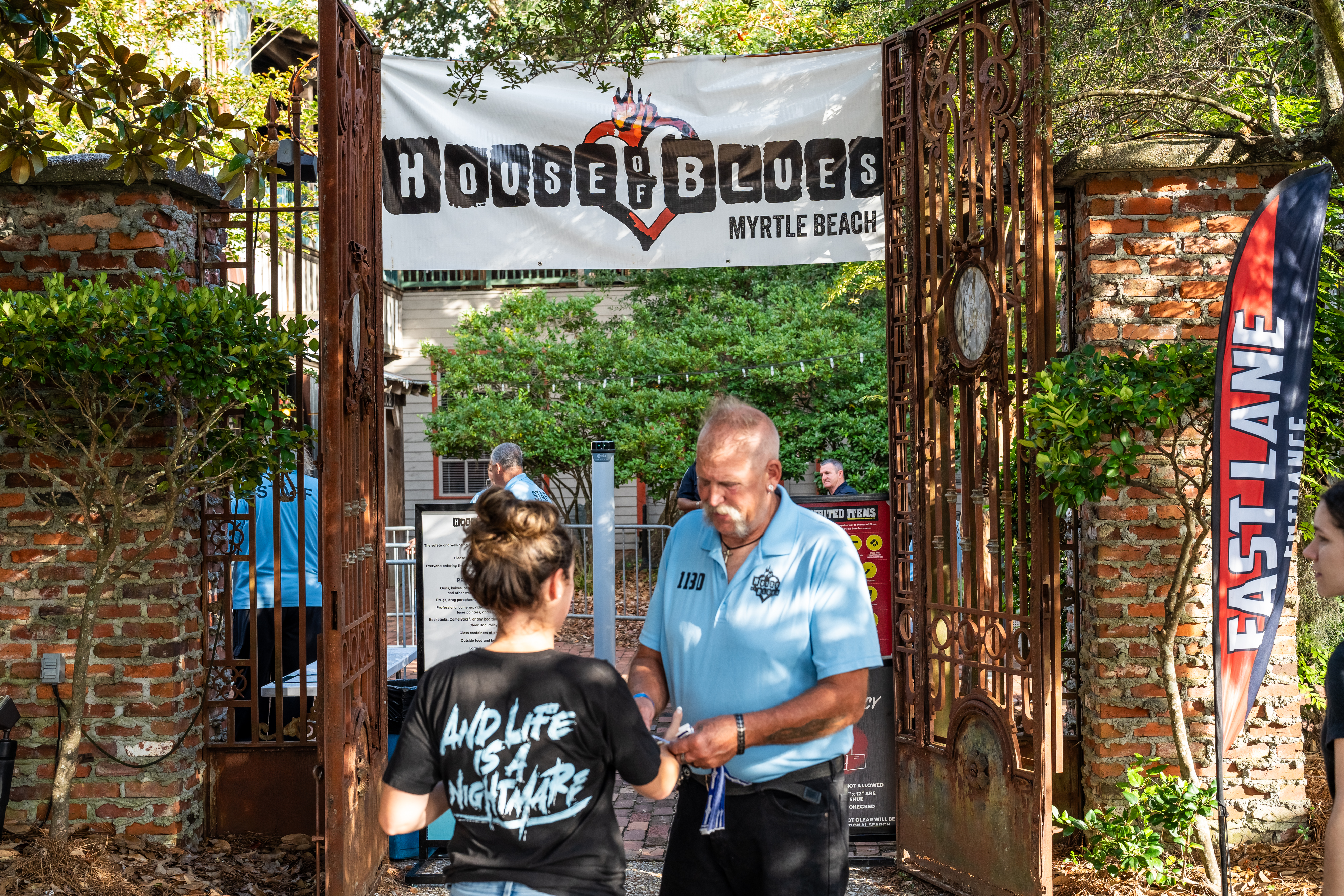 A security guard checking the ticket of a concert goer at the fast lane entrance to a show.