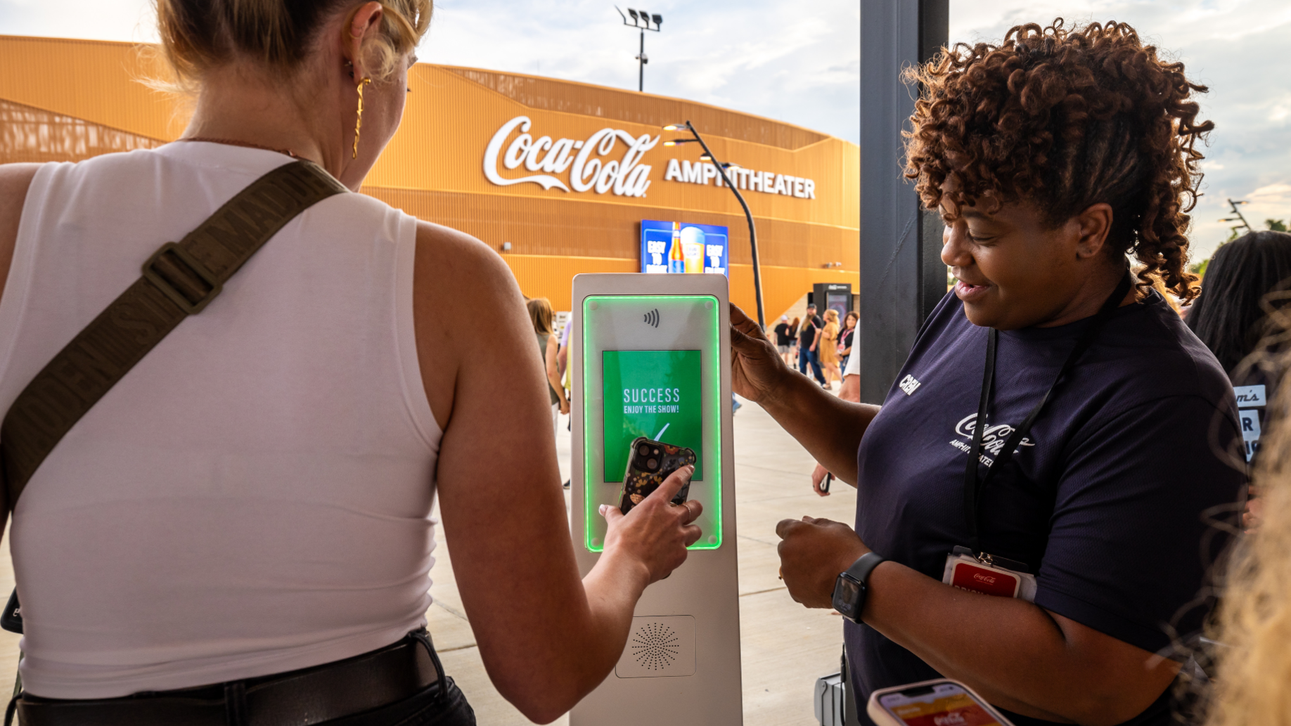 An employee watches as a fan scans their digital ticket for entry into the venue.