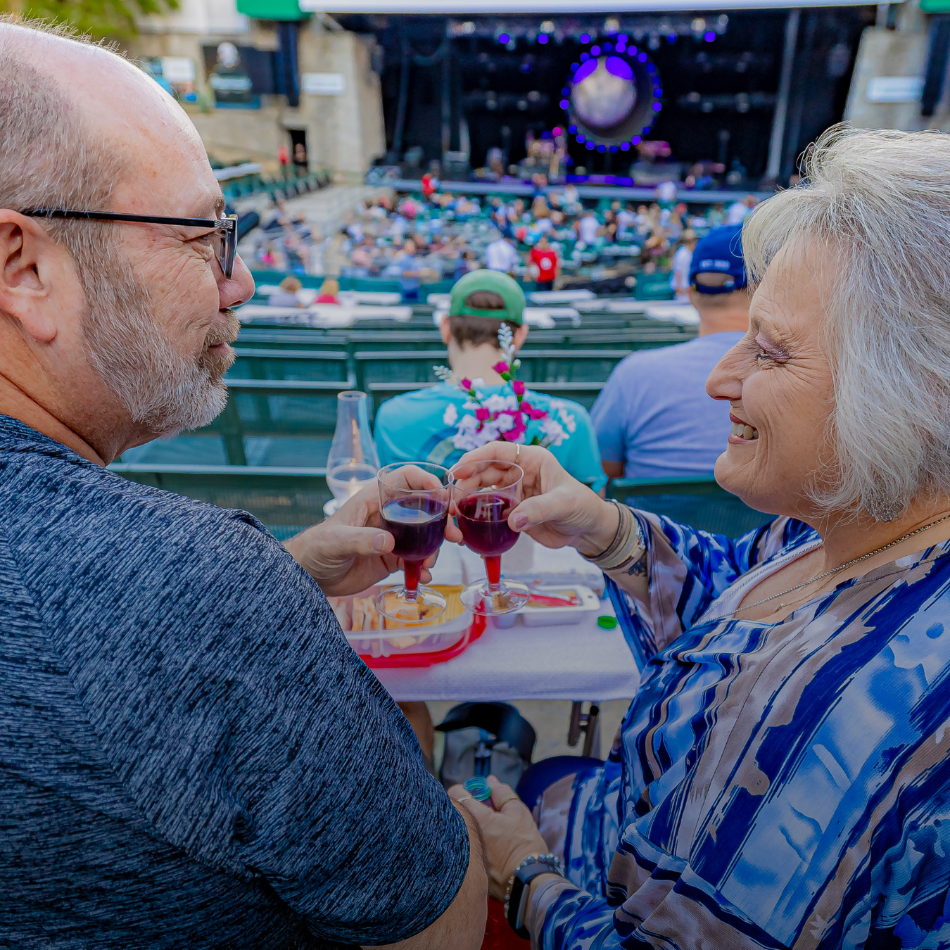 A couple cheers their drinks together at a concert.