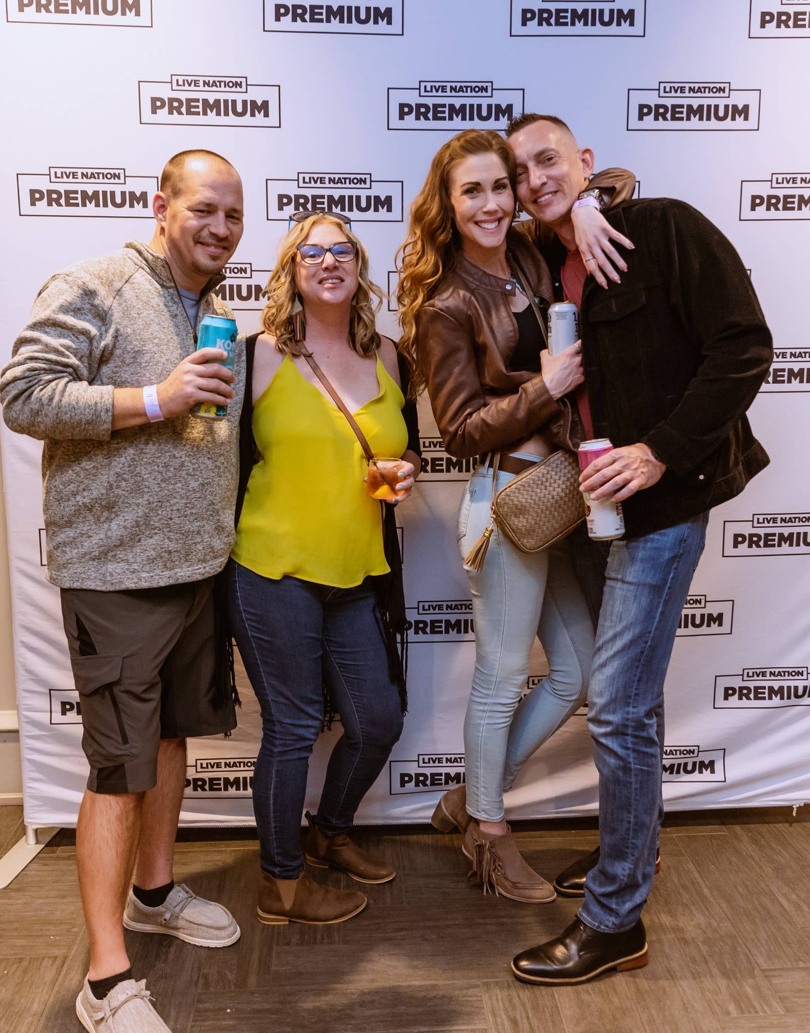 Four people smiling at the camera while holding drinks