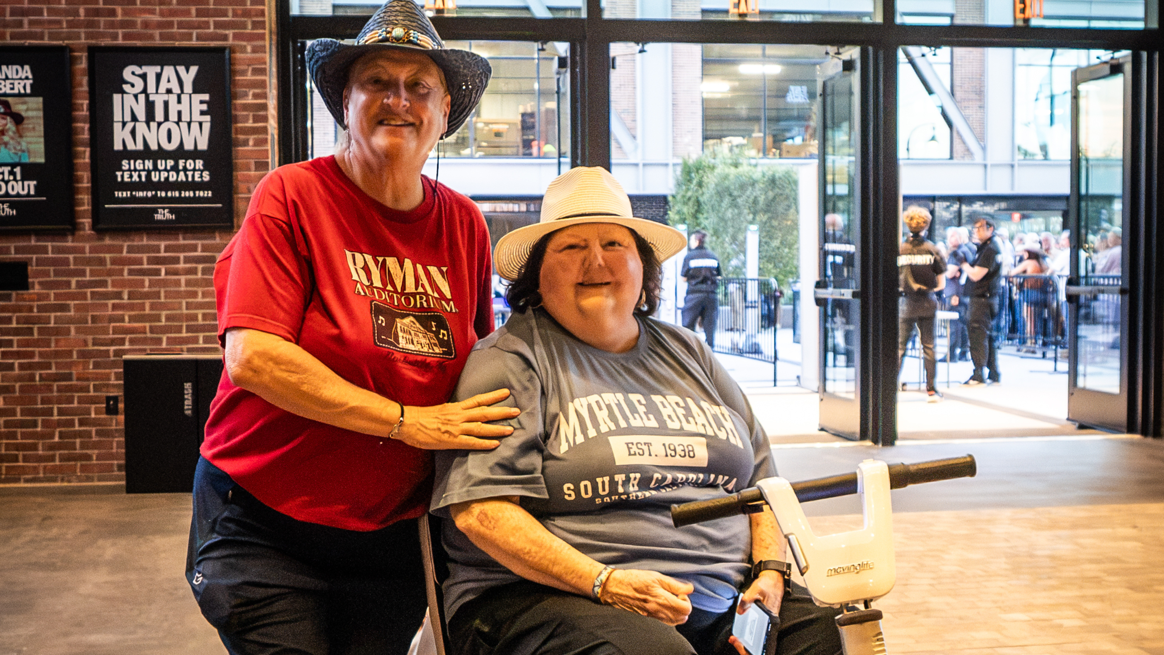 Two guests pose in The Truth’s lobby; one is seated on a mobility scooter.Photo credit: Alive Coverage