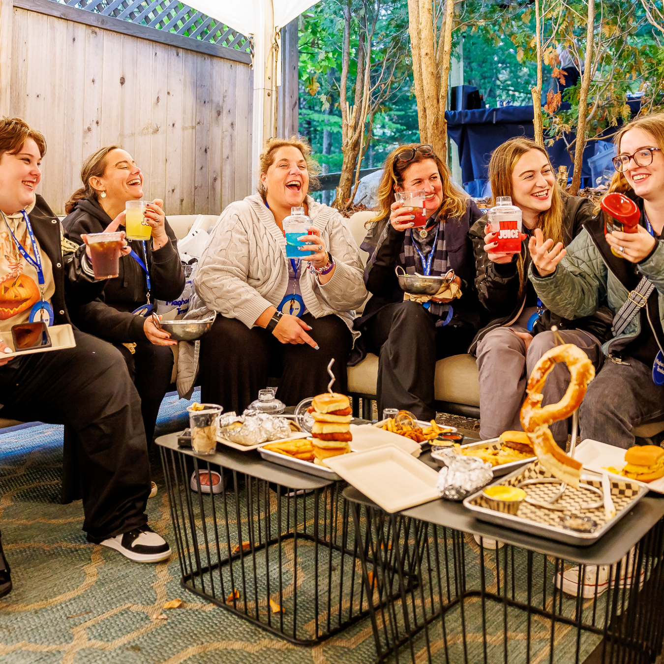 a group of 6 women laughing while enjoying a spread of VIP food offerings