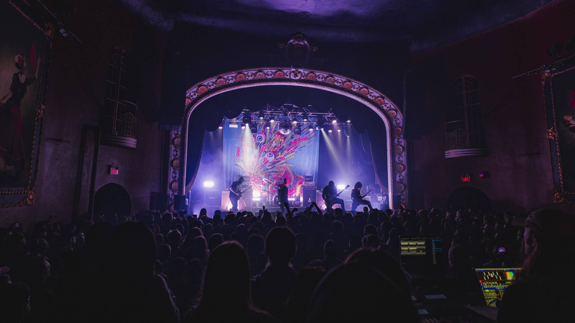 A room full of people enjoying a concert with a band on the stage