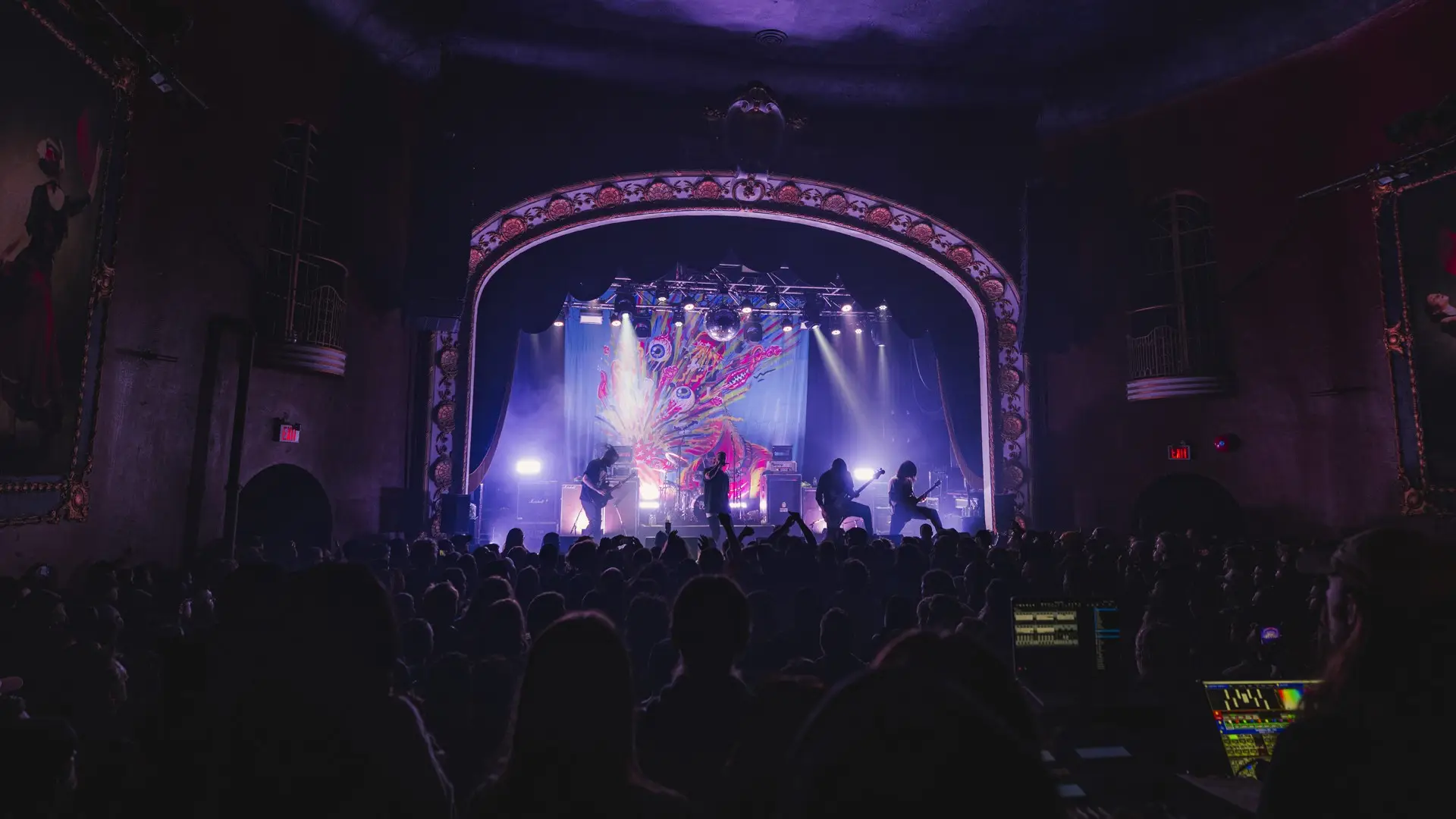 A room full of people enjoying a concert with a band on the stage