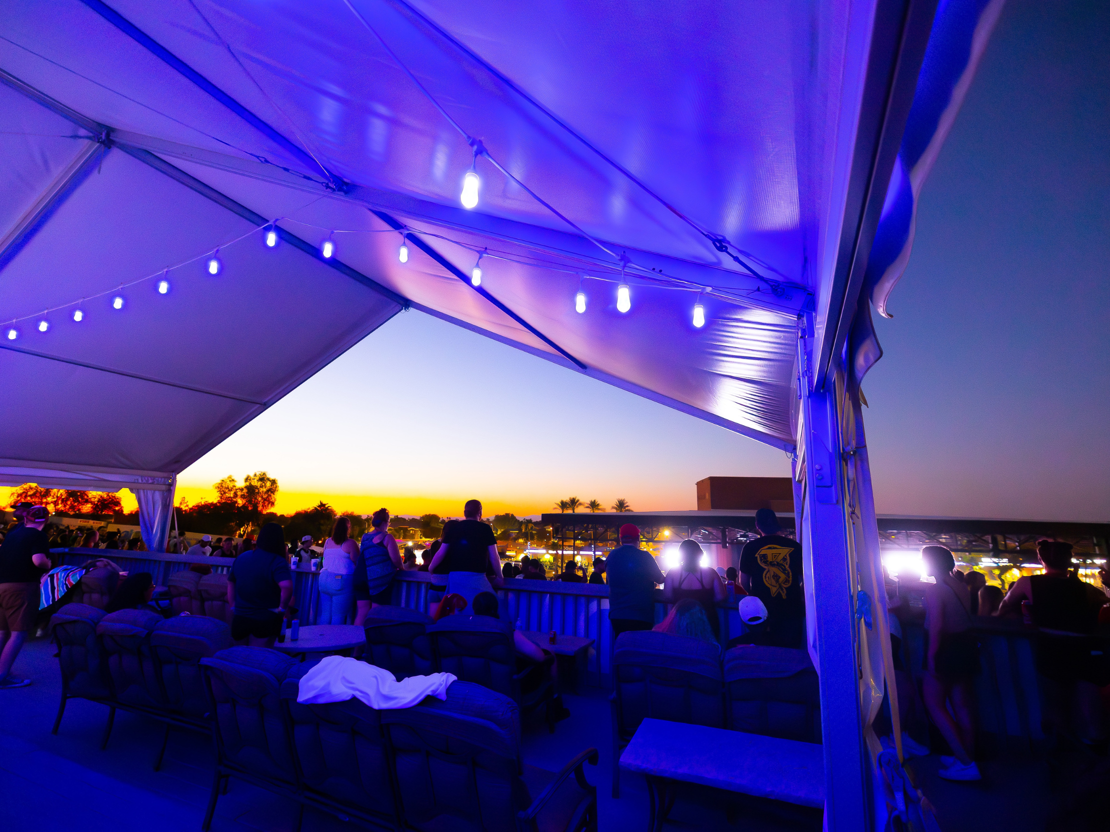 fans watching the show from the VIP club with a sunset in the background