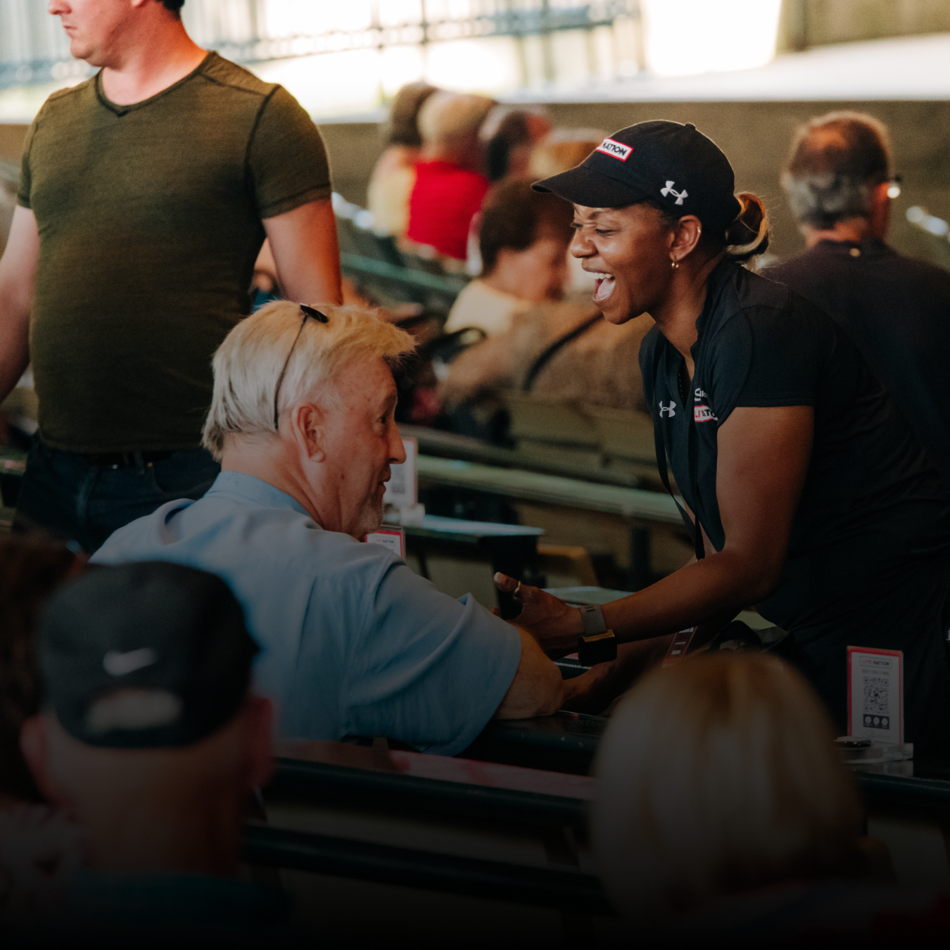 A seat attendant interacting with a fan, taking a food or beverage order from in-seat.