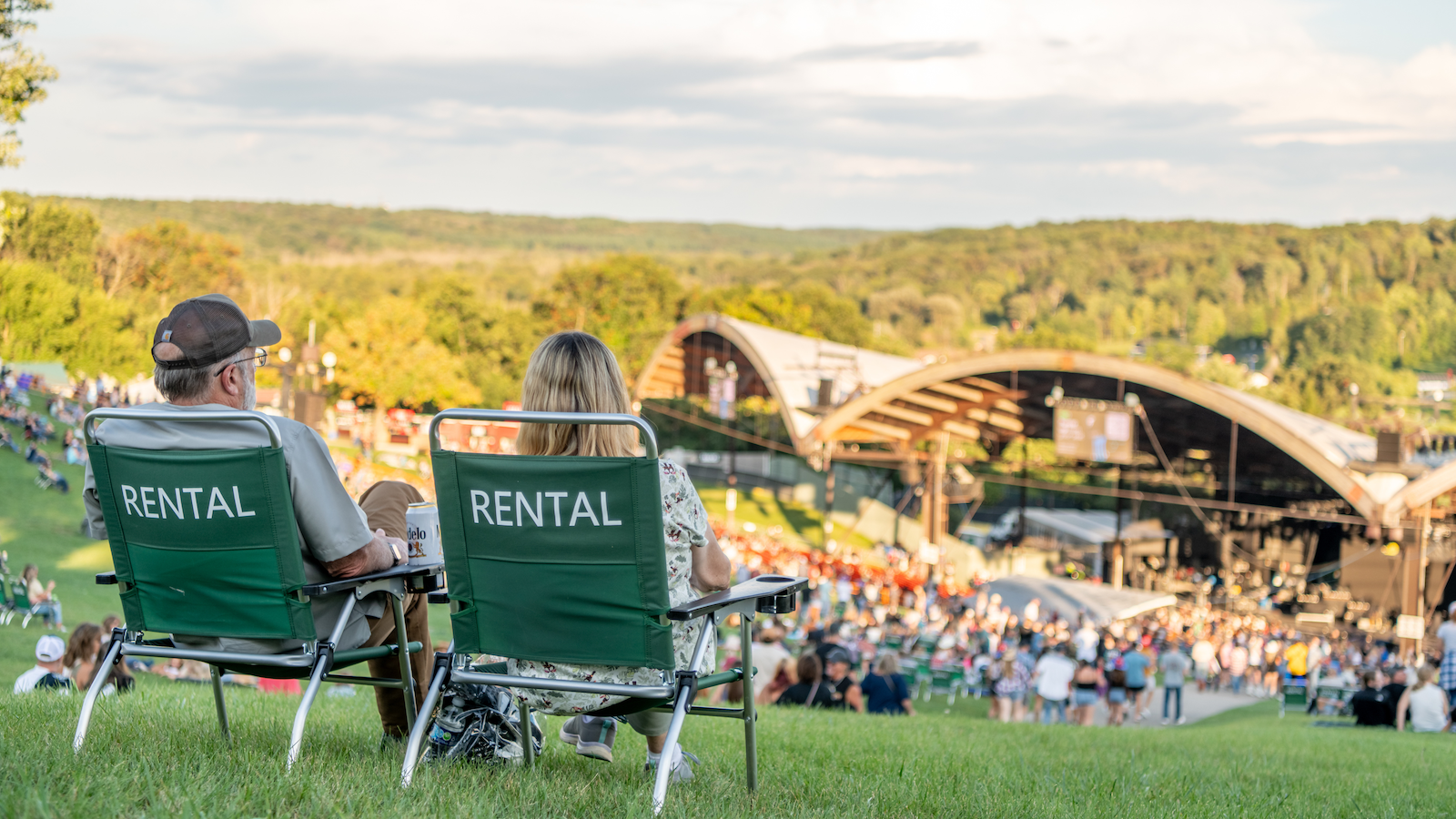 Attendees sitting in rental chairs on the lawn facing the amphitheatre