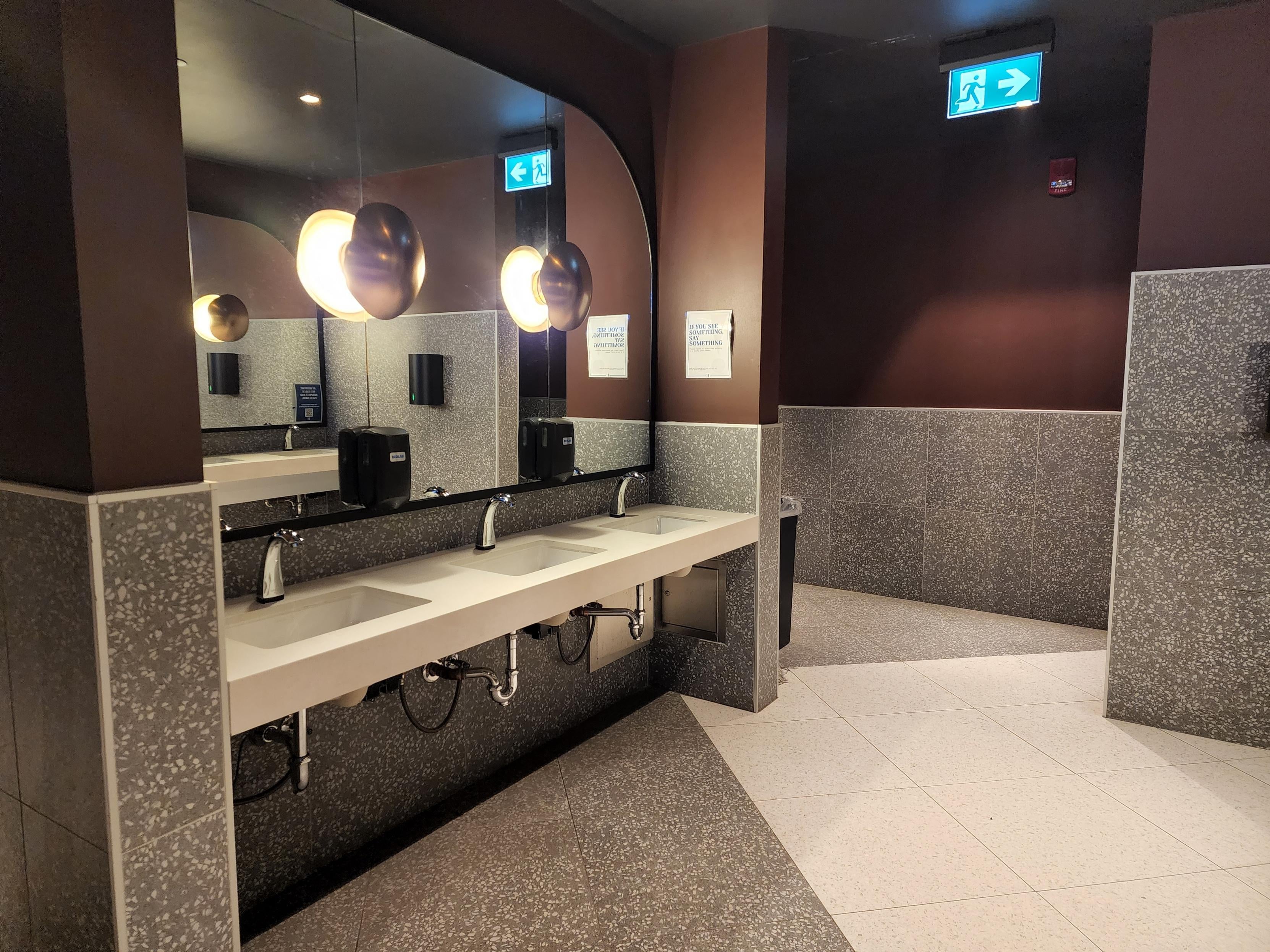 Washroom with large walkway and mirrors as well as 3 visible sinks/faucets
