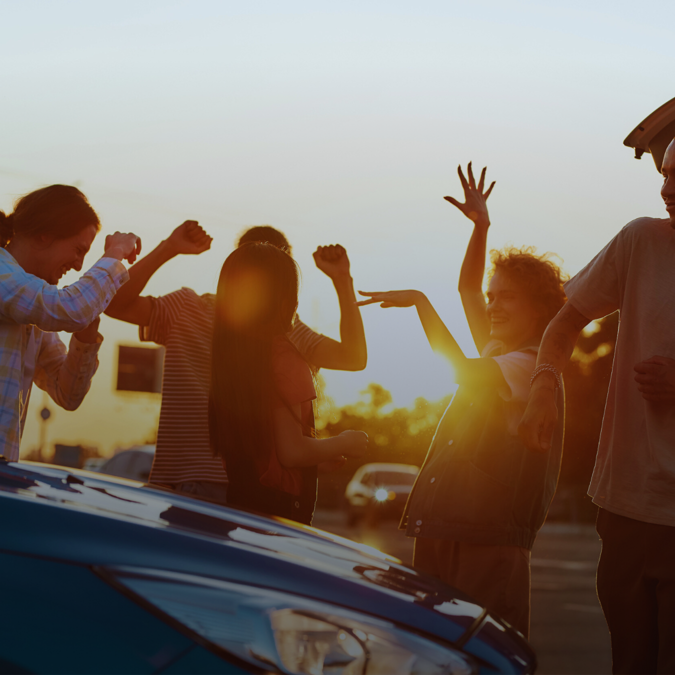 A group of people dancing around a car.