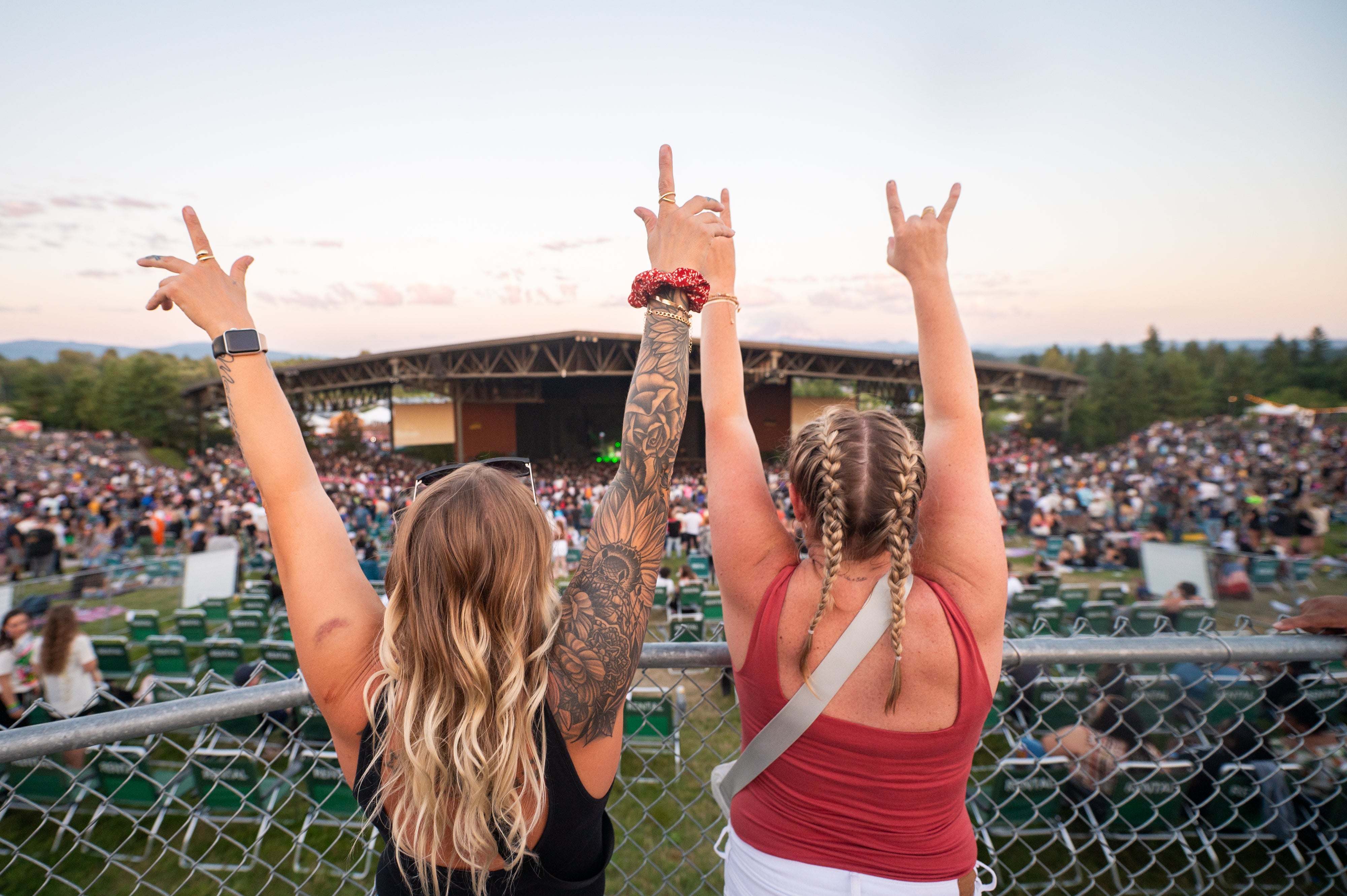 two girls with their hands up and the venue in the background 
