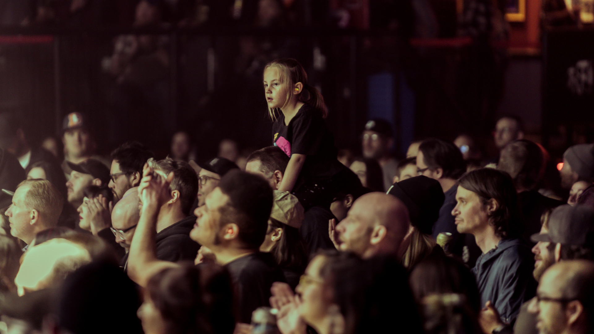 Photo of a young fan on someones shoulders above the crowd 