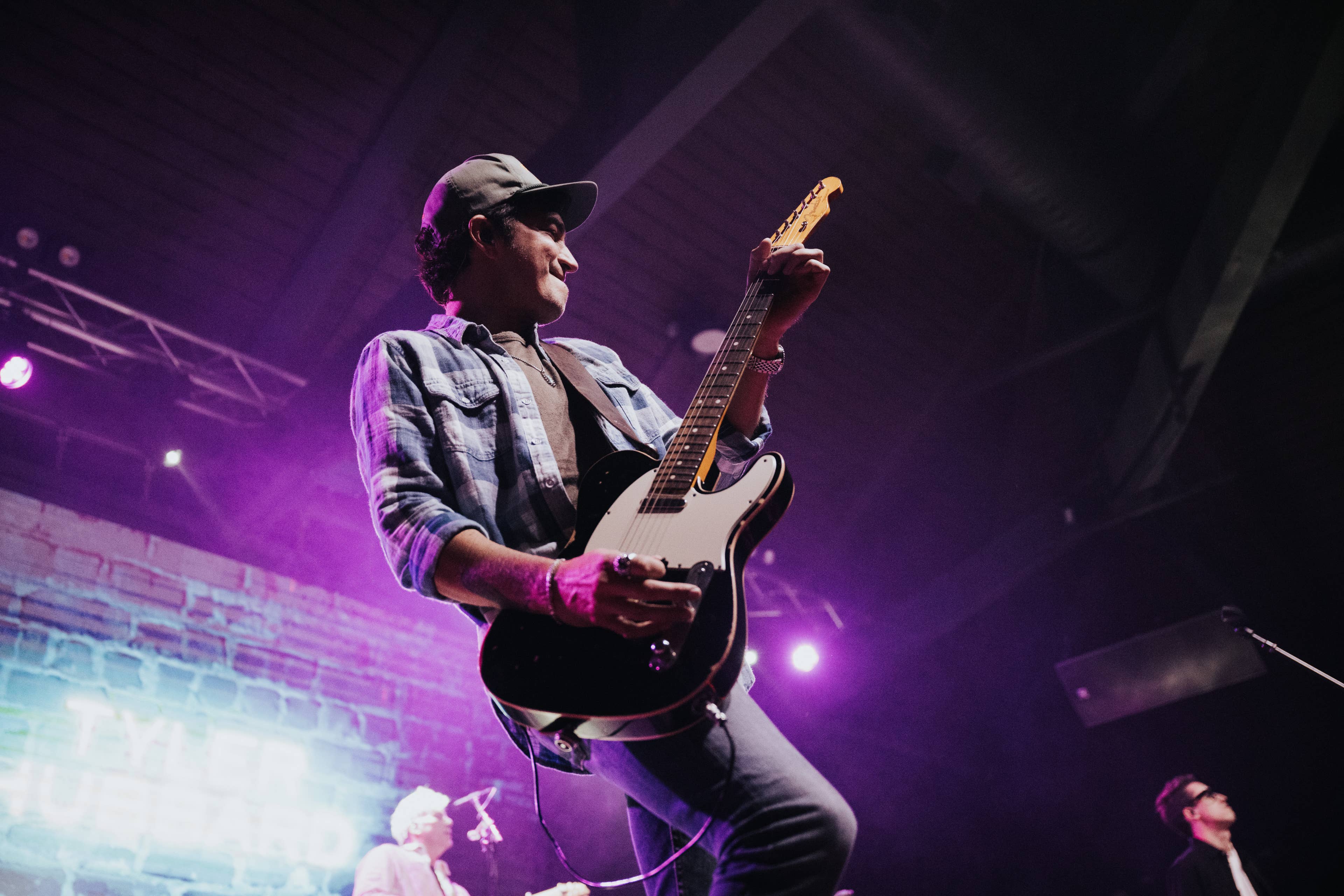 view of an artist with a guitar on stage up close