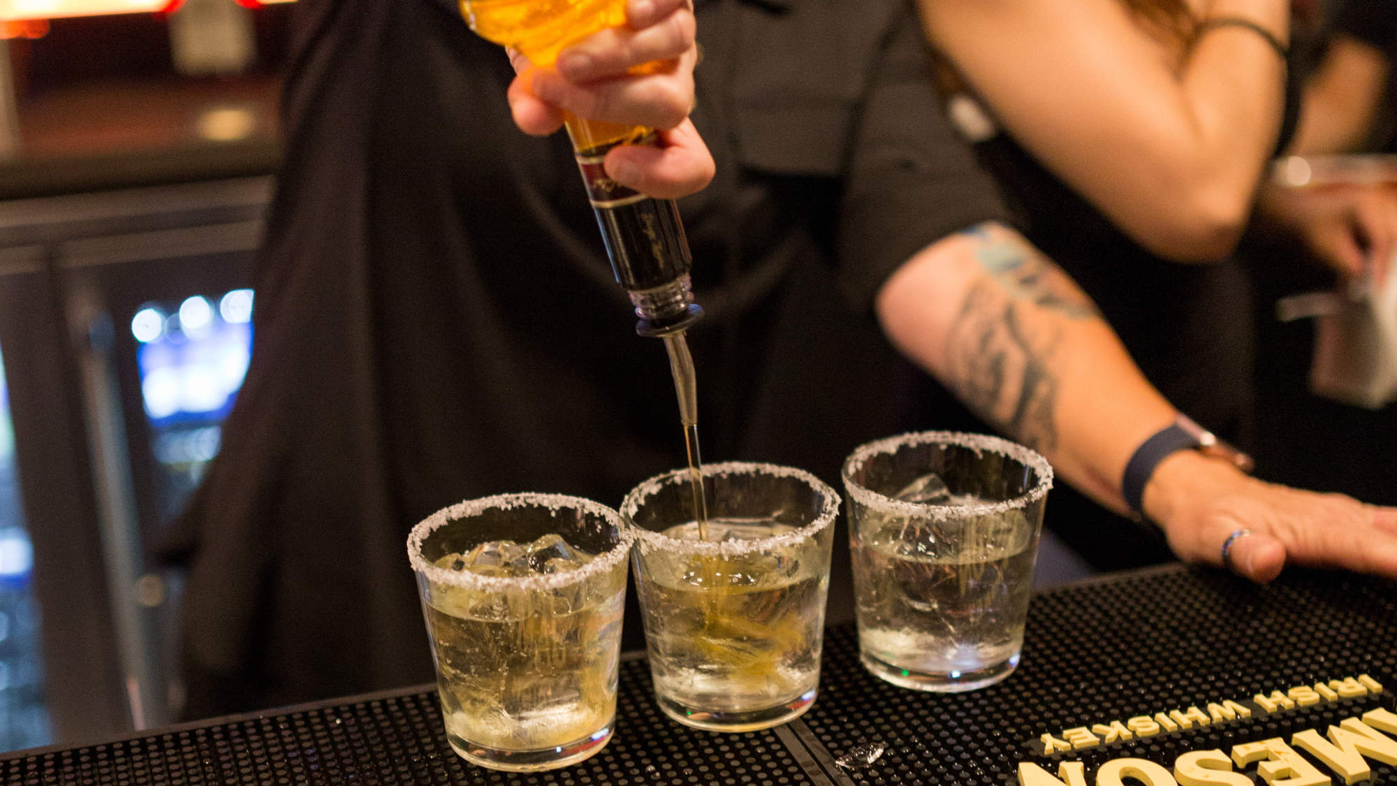 Bartender pouring three shots with a salt rim.