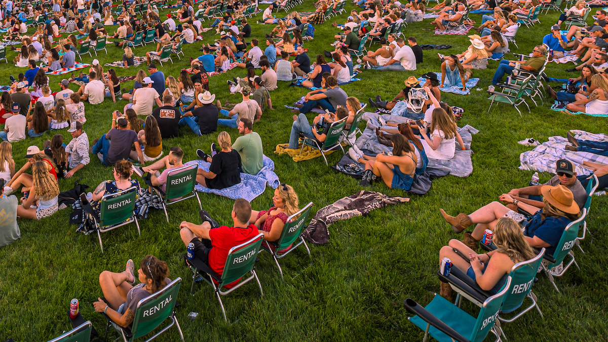 Fans are seen sitting in lawn chairs at a concert.