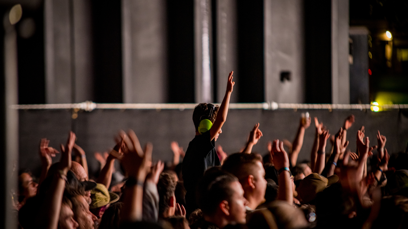 Kid with hands up at a concert.
