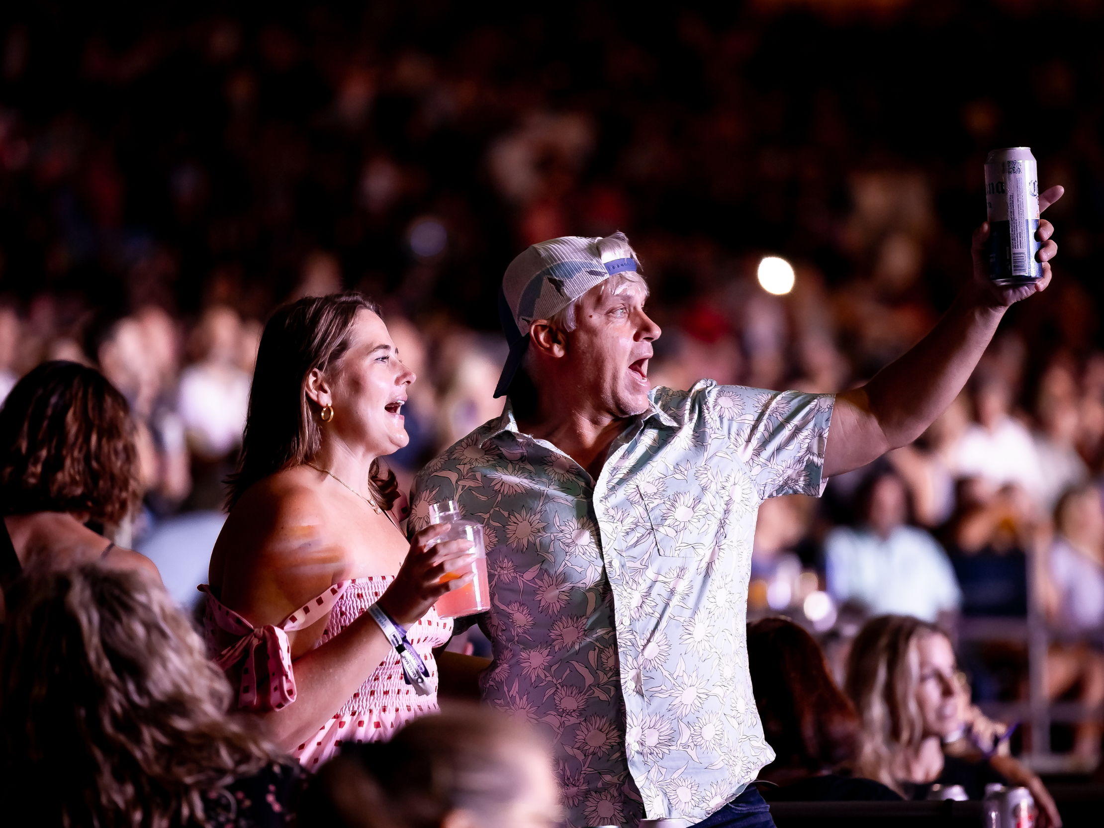 A couple, holding their drinks to the stage and singing.