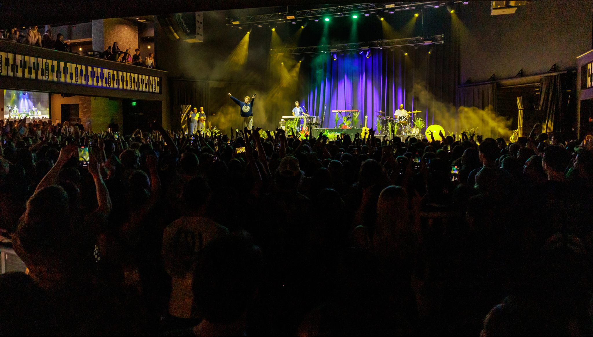 A view of a performer on stage raising his hands at the crowd