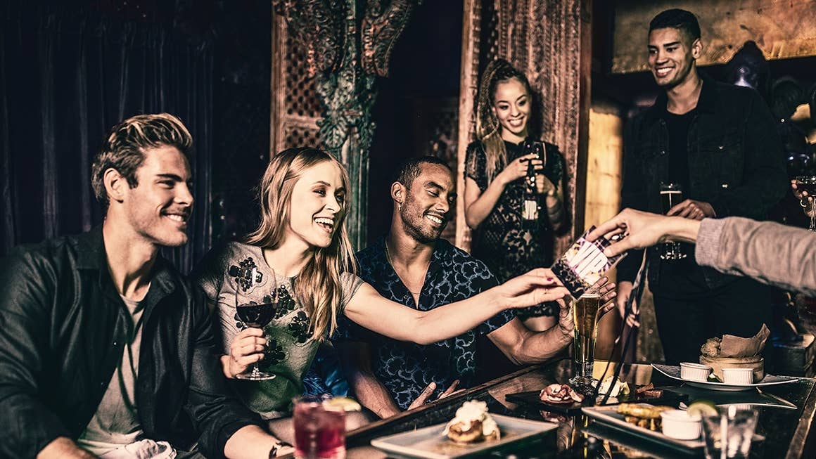 A group of people at a table getting handed VIP passes