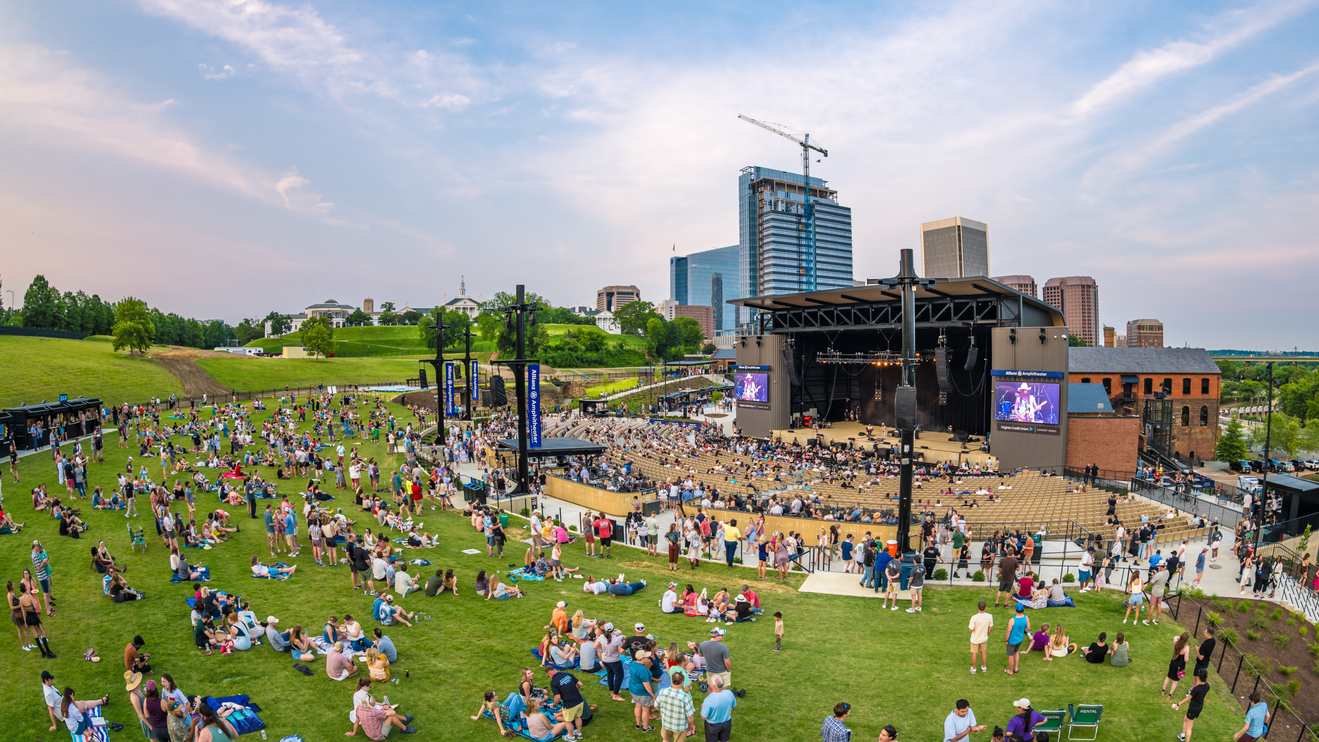 Aerial view of the venue during the day with fans on the lawn and a view of the Richmond city skyline.