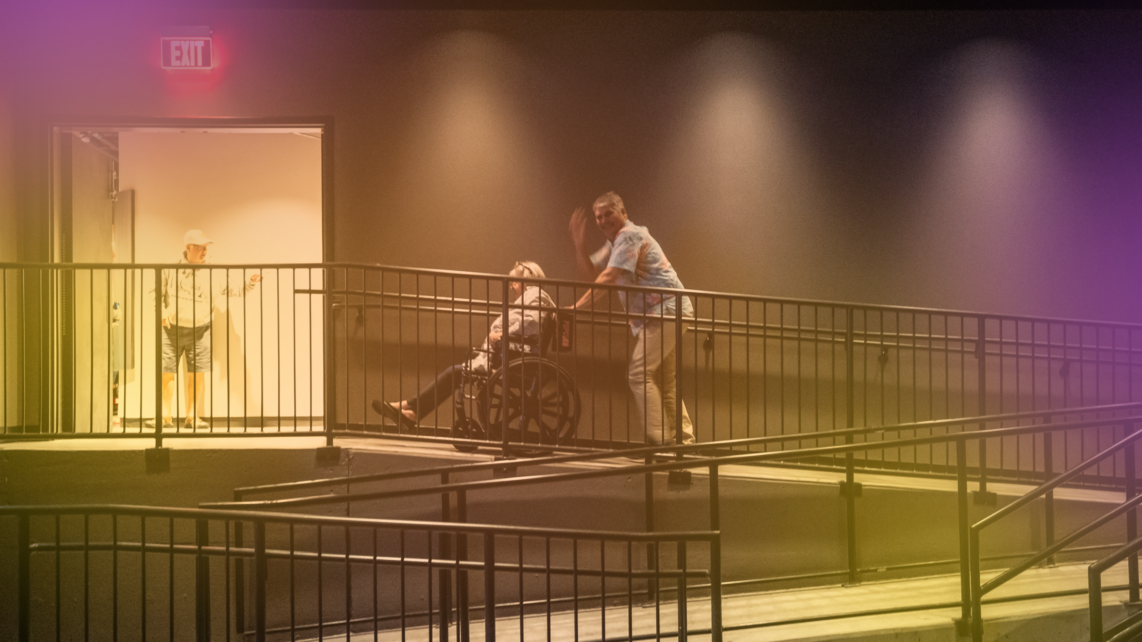 A man pushing a wheelchair up a ramp. 