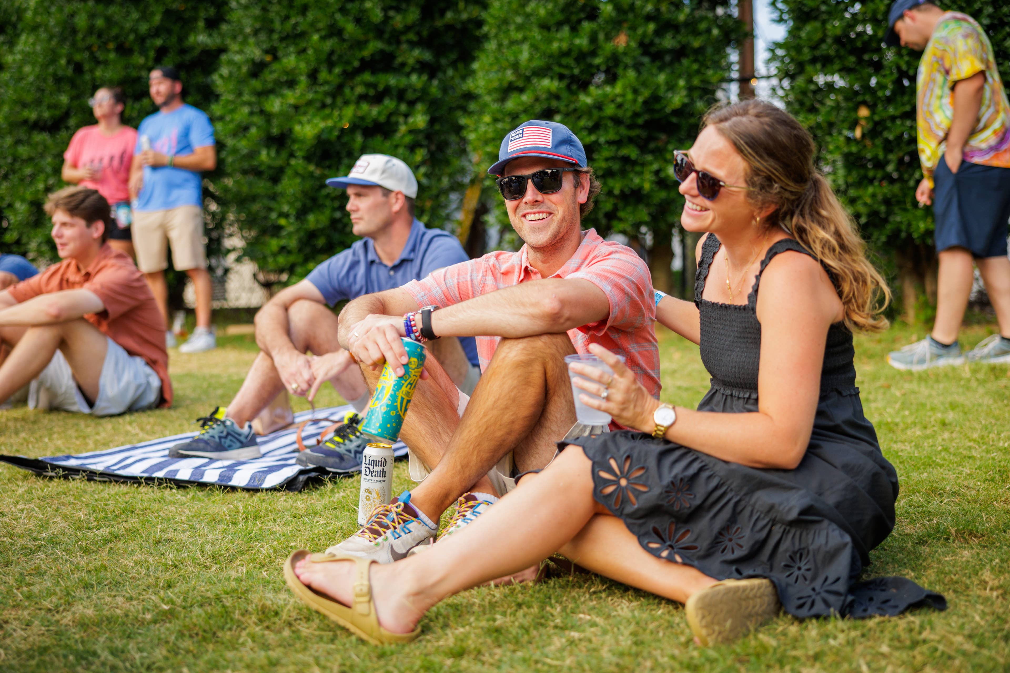 A couple sitting on the lawn area smiling at Skyla Credit Union Amphitheatre.
