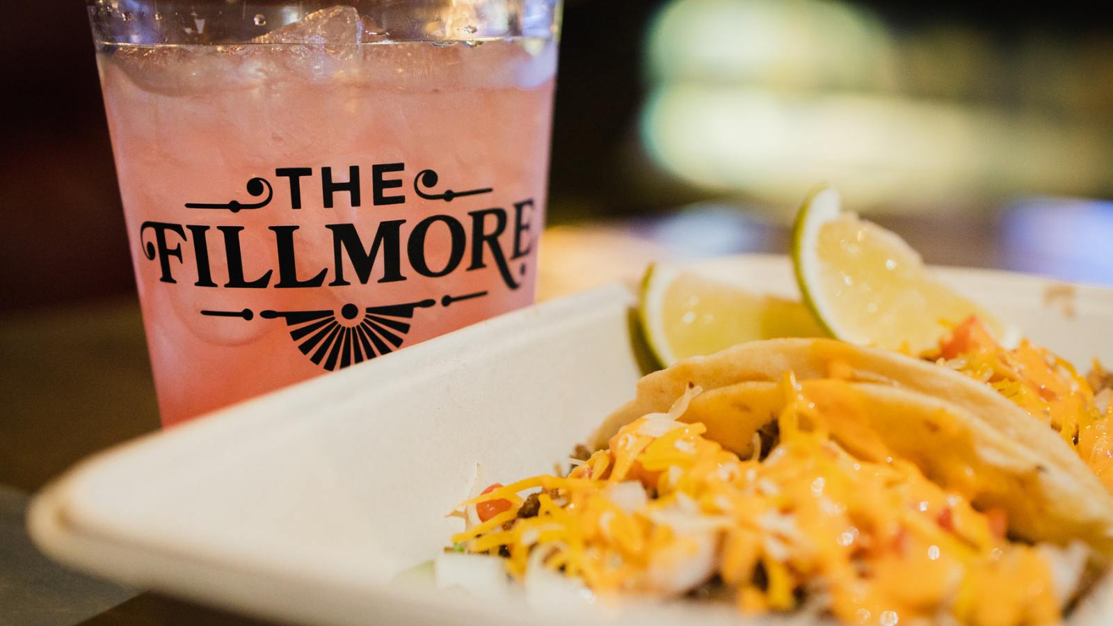 A drink in a cup with The Fillmore logo and tacos.