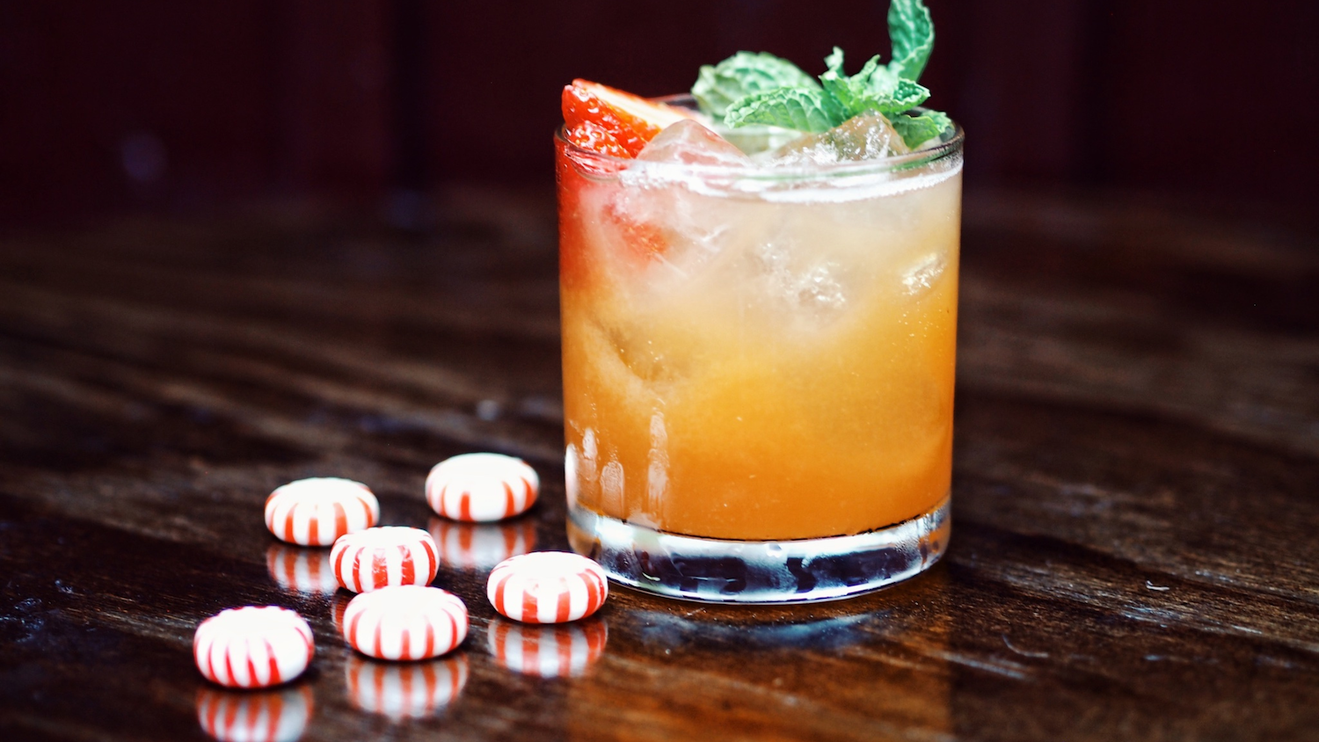 A cocktail drink with peppermint candy on a table