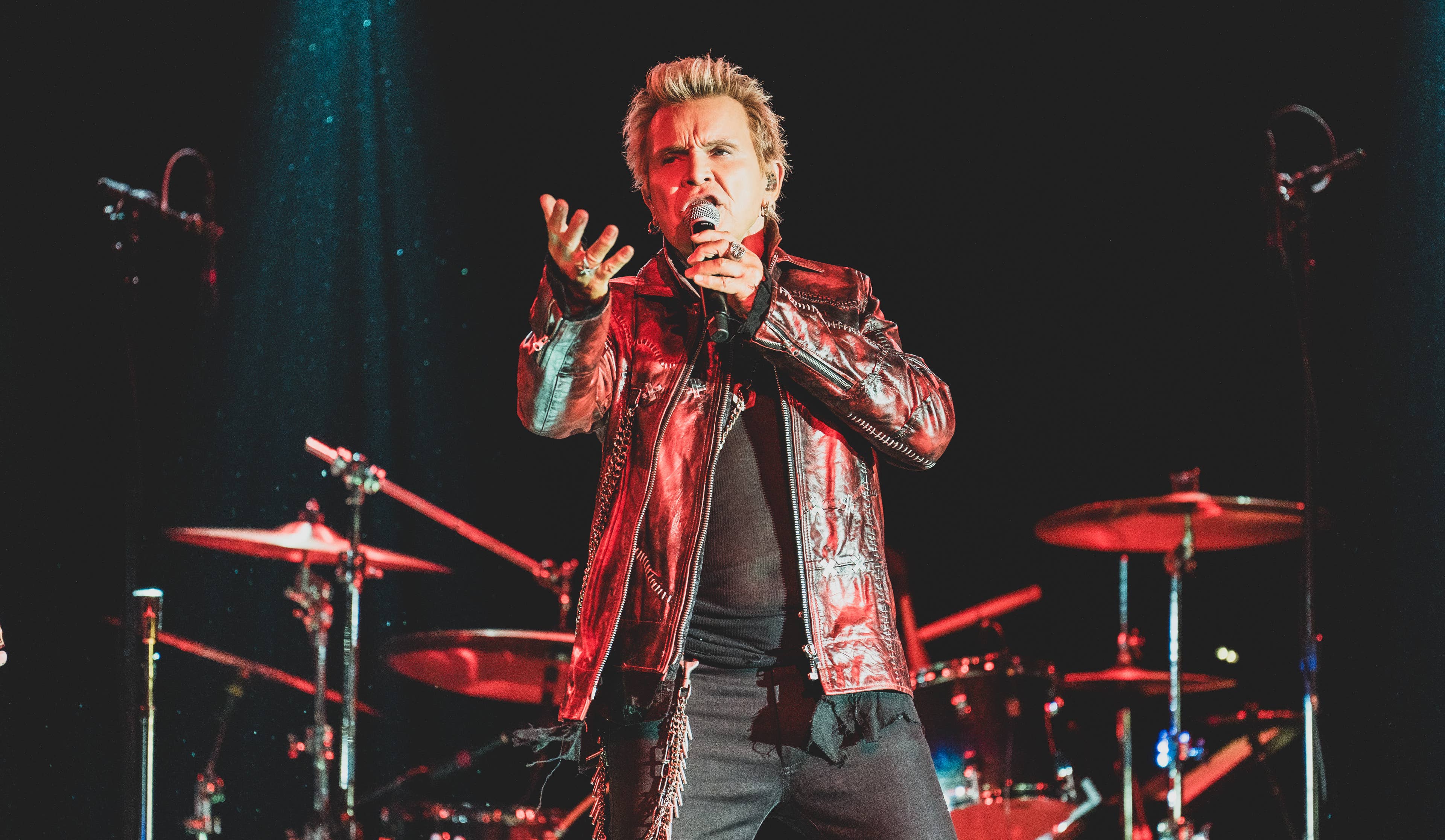 photo of billy idol singing into a microphone with his arm extended