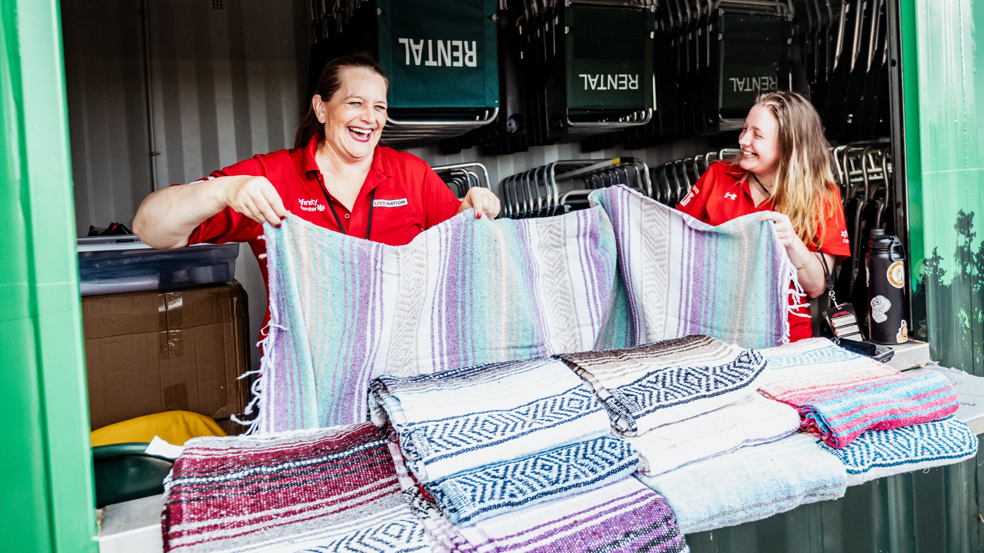 Two employees hold up blankets at the blanket rental stand.